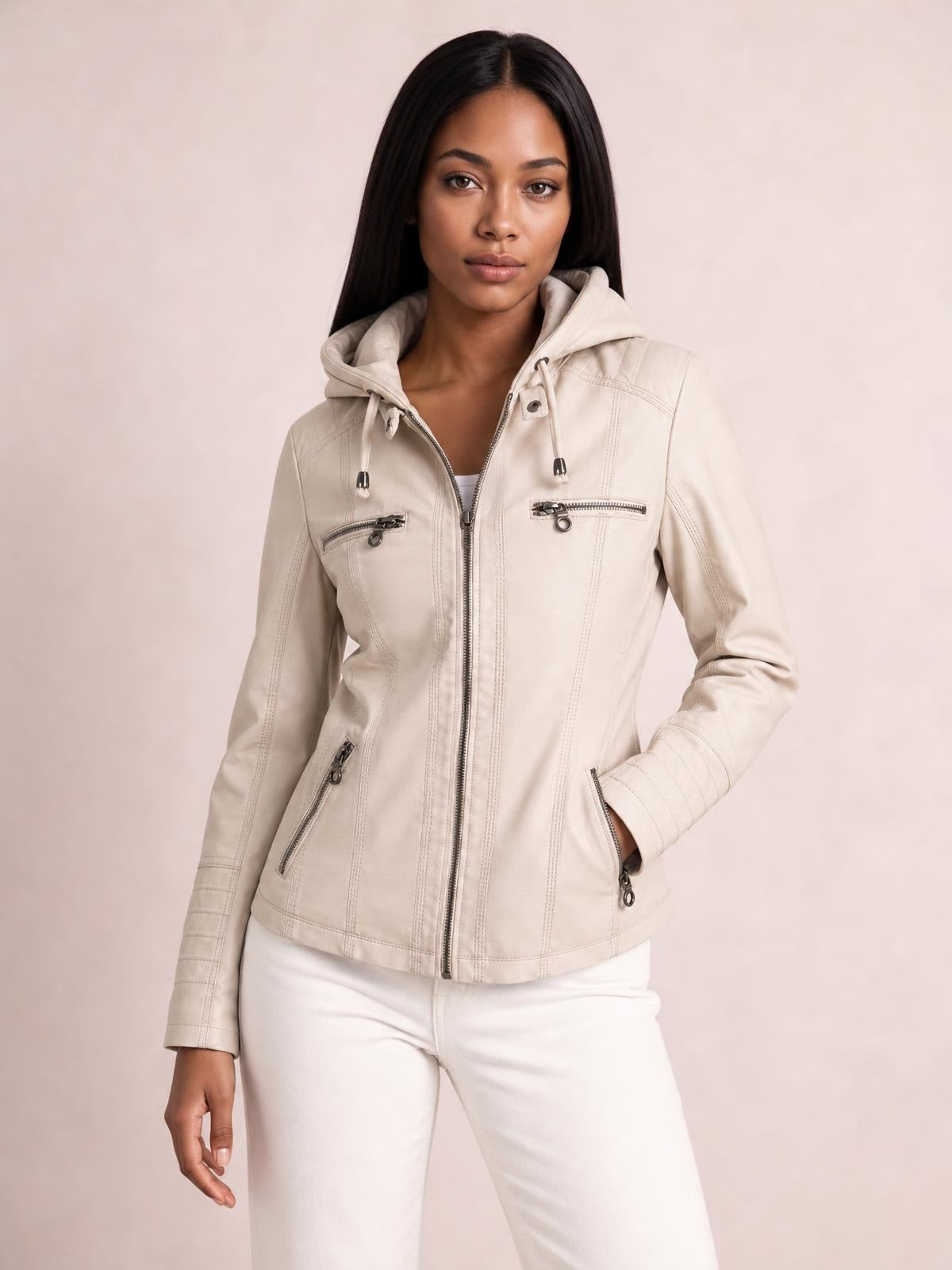 Model poses in a cream faux leather moto jacket with hood, drawstrings, zip closure, seam detailing, and multiple zippered pockets in a regular fit.