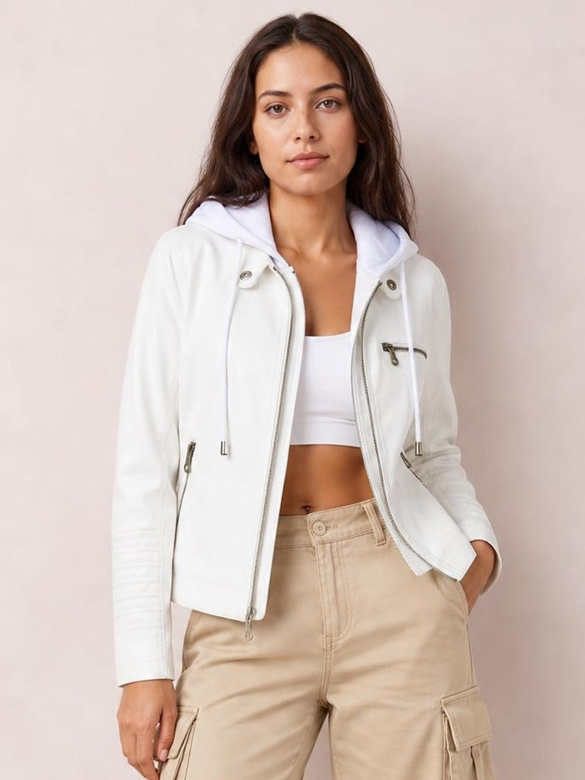 A model wears a white faux leather moto jacket with a hood, asymmetric zip closure, seam details, zippered pockets, and a regular cropped silhouette.