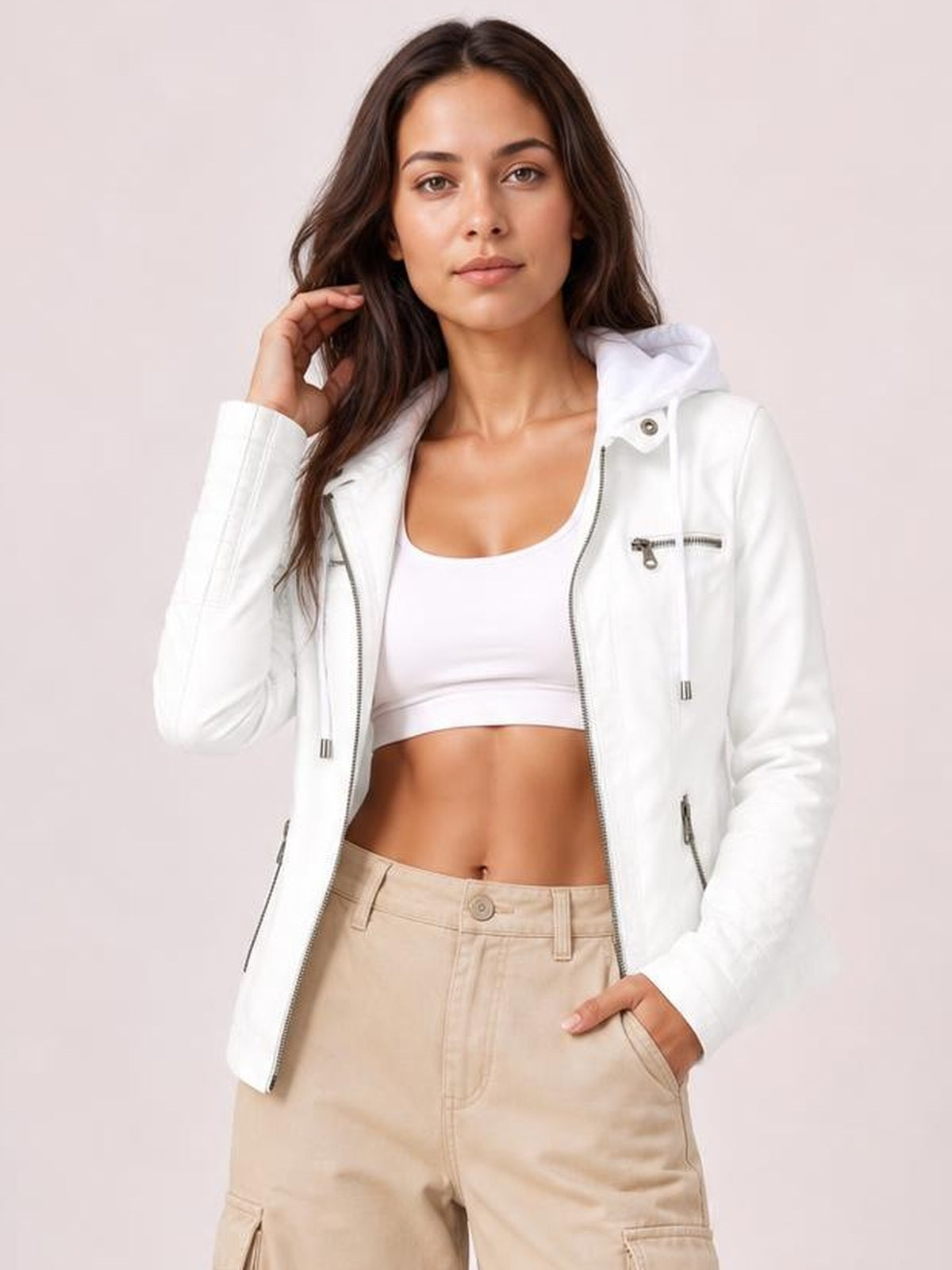 Model poses in a white faux leather moto jacket with a hood, open front zipper, seam detailing, zip pockets, and a regular silhouette.