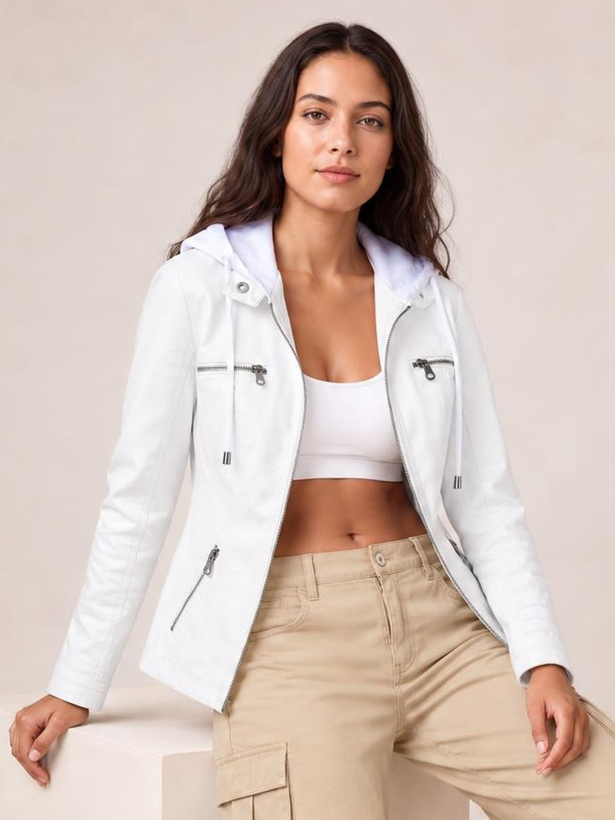 A model poses in a white faux leather moto jacket with a hood, zip closure, seam detailing, zippered pockets, and a regular silhouette.