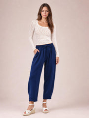 A model stands in navy drawstring cropped jogger pants with an elastic waist, relaxed straight-leg silhouette, and side pockets, one hand tucked inside.