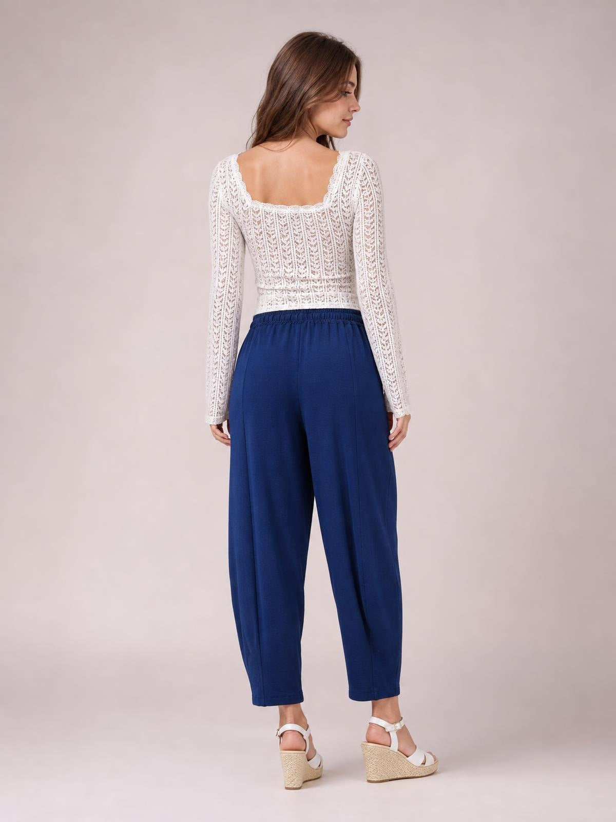 A model poses in navy cropped jogger pants with a gathered elastic waistband, relaxed straight-leg silhouette, and ankle-length hems.