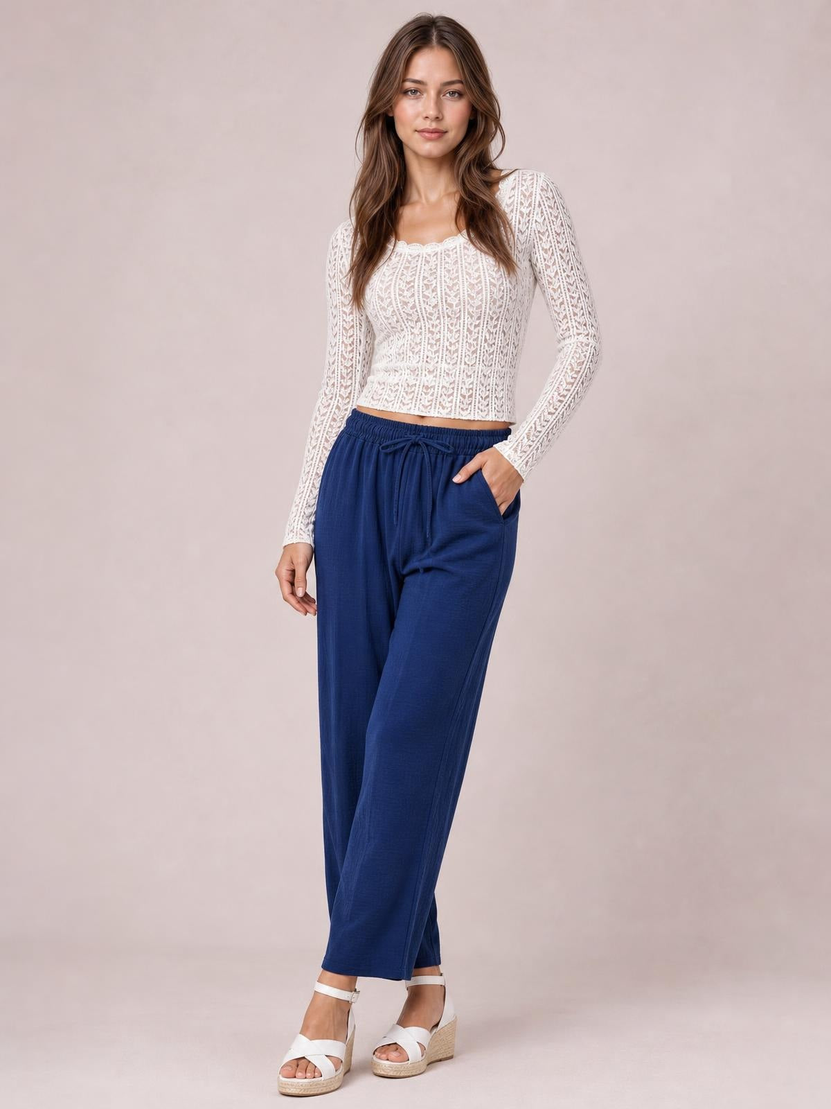 A model poses in navy cropped jogger pants with an elastic drawstring waist, side pockets, and a relaxed straight-leg silhouette.