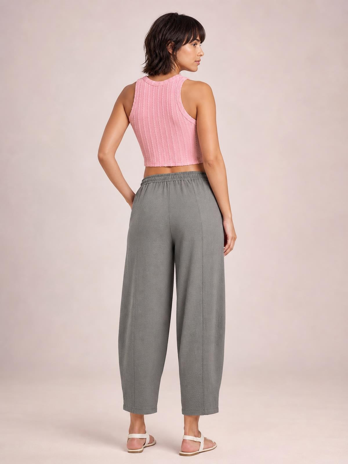 A model poses from the back in gray cropped jogger pants with an elastic waistband, relaxed wide-leg silhouette, and ankle-length hems.