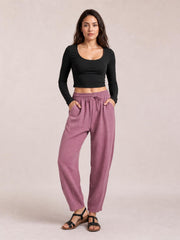 A model stands wearing mauve cropped jogger pants with a relaxed tapered silhouette, elastic drawstring waist, and roomy side pockets.