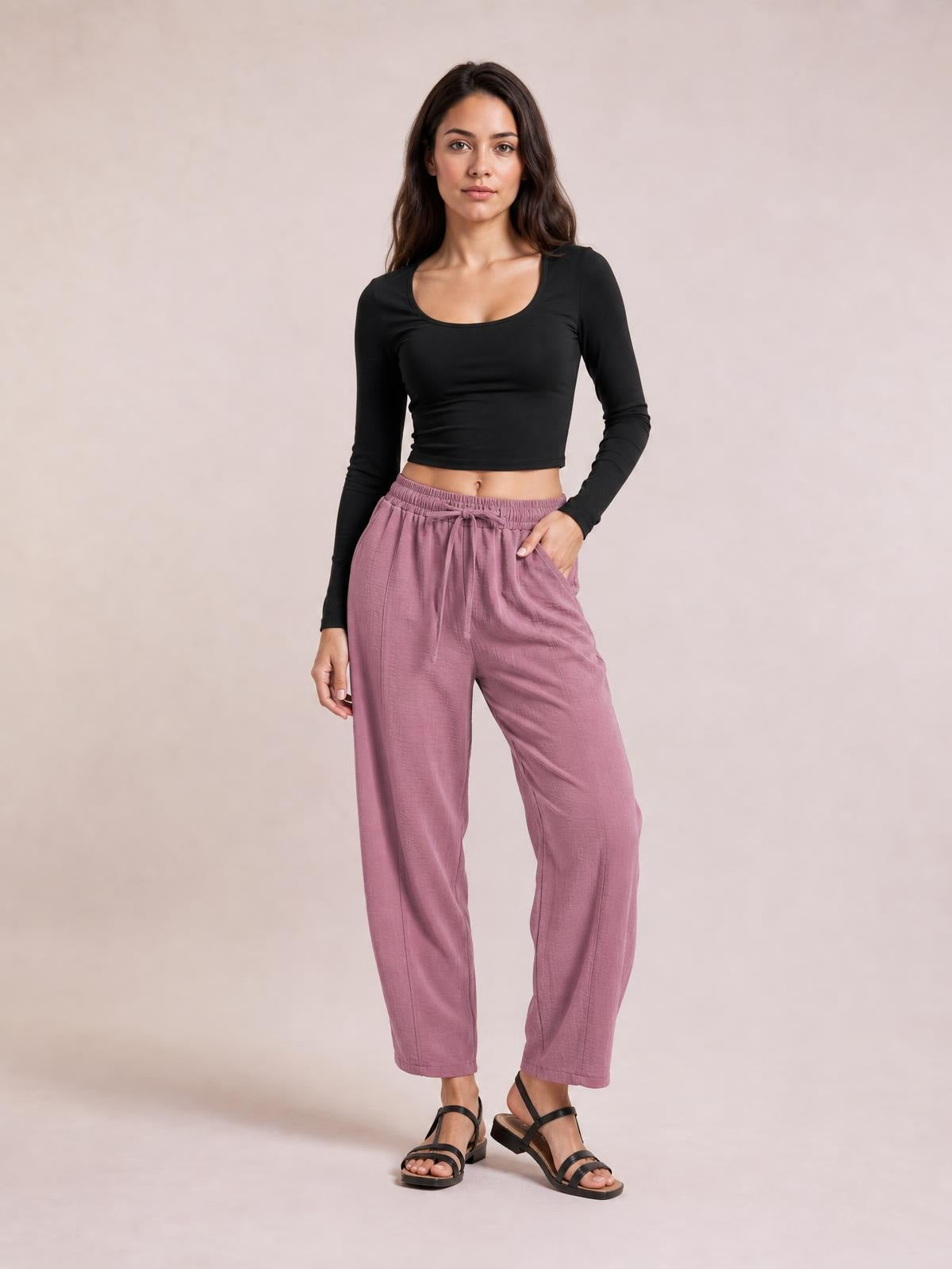 Model poses in mauve cropped jogger pants with an elastic drawstring waist, relaxed tapered silhouette, and side pockets.