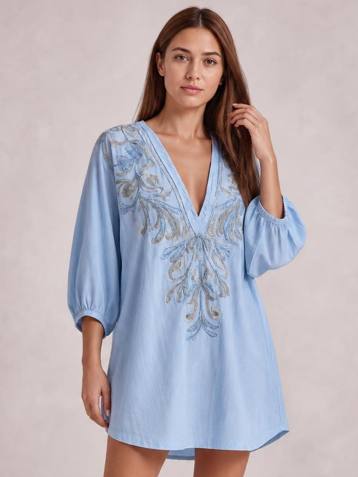 A model poses in a light blue embroidered V-neck mini dress with a loose A-line silhouette, balloon sleeves, and a short straight hem.