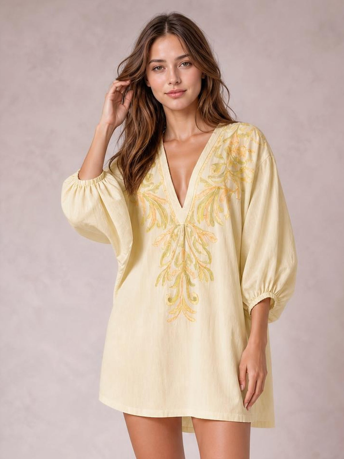 Model poses in a cream embroidered V-neck mini dress with a loose A-line silhouette, long puff sleeves, and gathered cuffs.