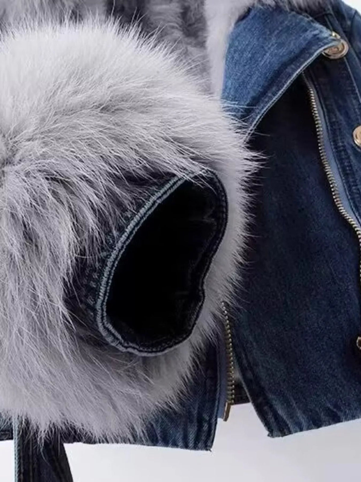 Close-up of a dark blue denim jacket featuring a plush gray faux fur collar, zip-front closure, and structured construction.