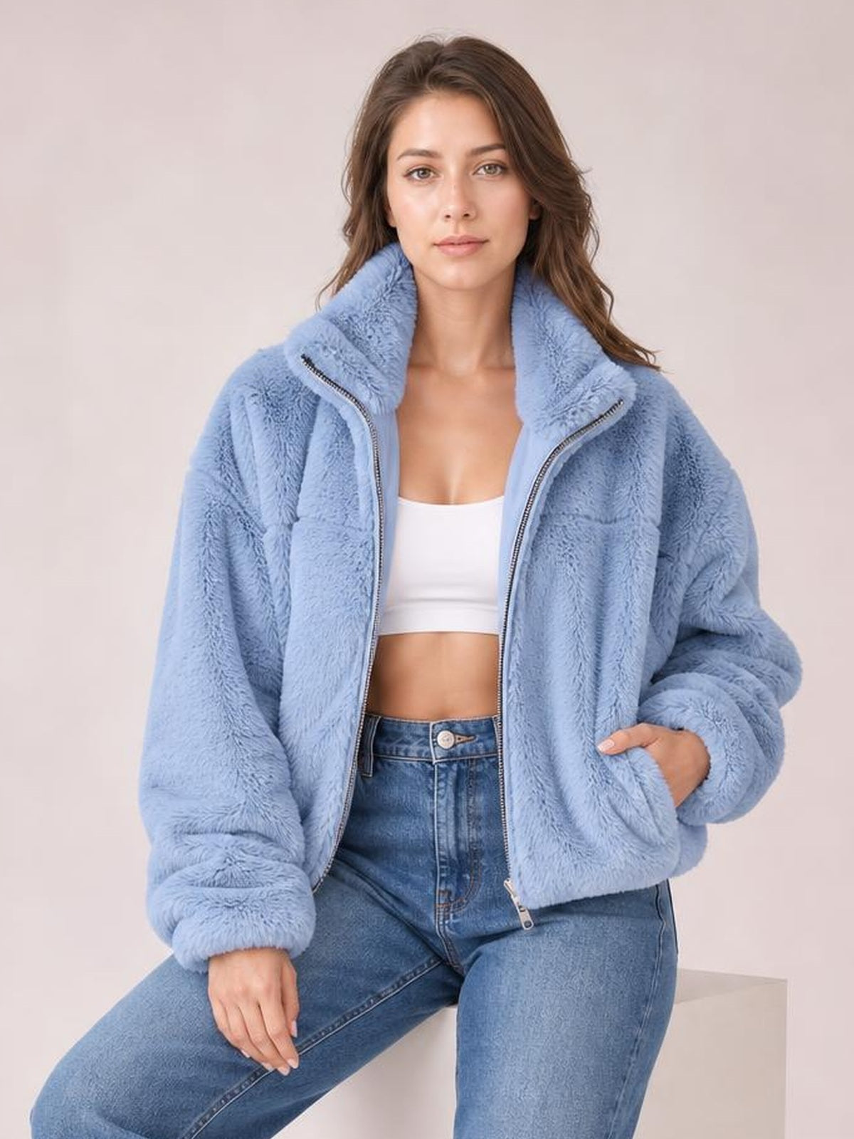 Model wearing a light blue oversized faux fur cropped zip-up jacket with a plush texture, stand collar, silver front zipper, and voluminous sleeves.