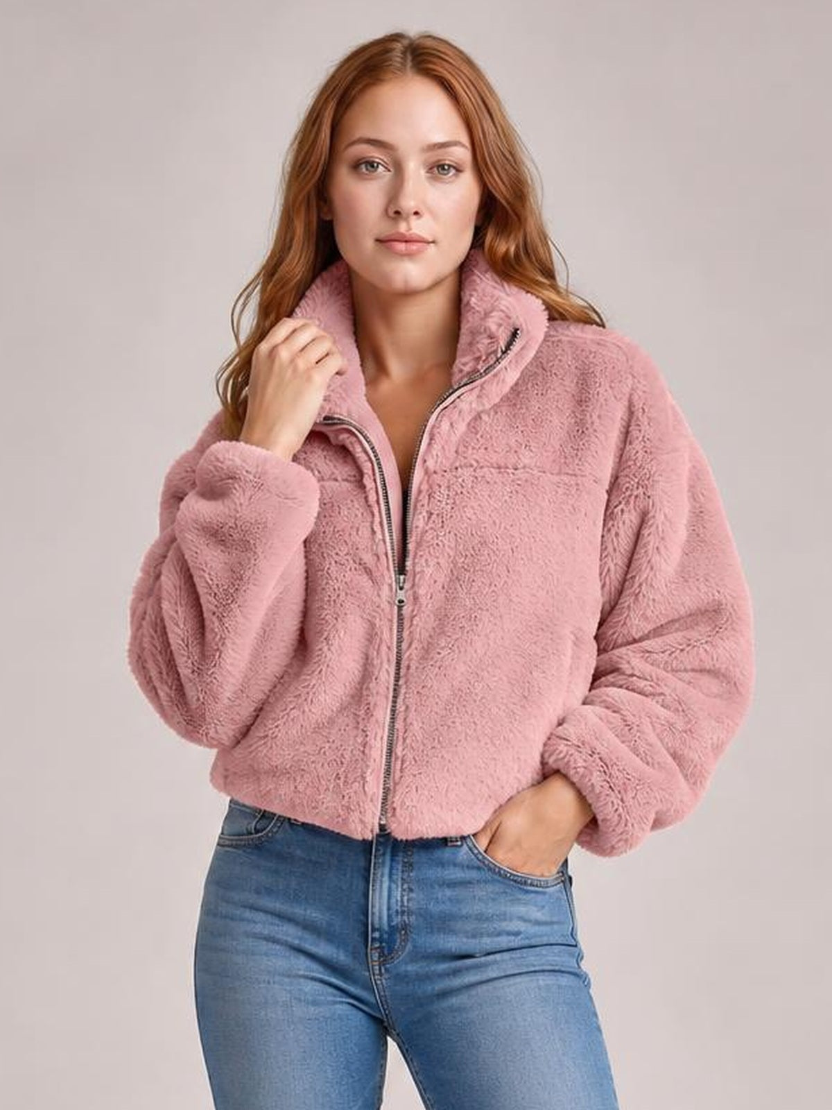 Model wearing a pink oversized faux fur cropped jacket with a plush texture, zip-front closure, high collar, and voluminous sleeves.