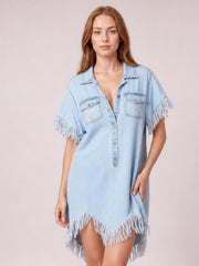 Model wears a light blue denim shirt dress with a button front, pointed collar, chest pockets, relaxed silhouette, and fringe trim on short sleeves and hem.