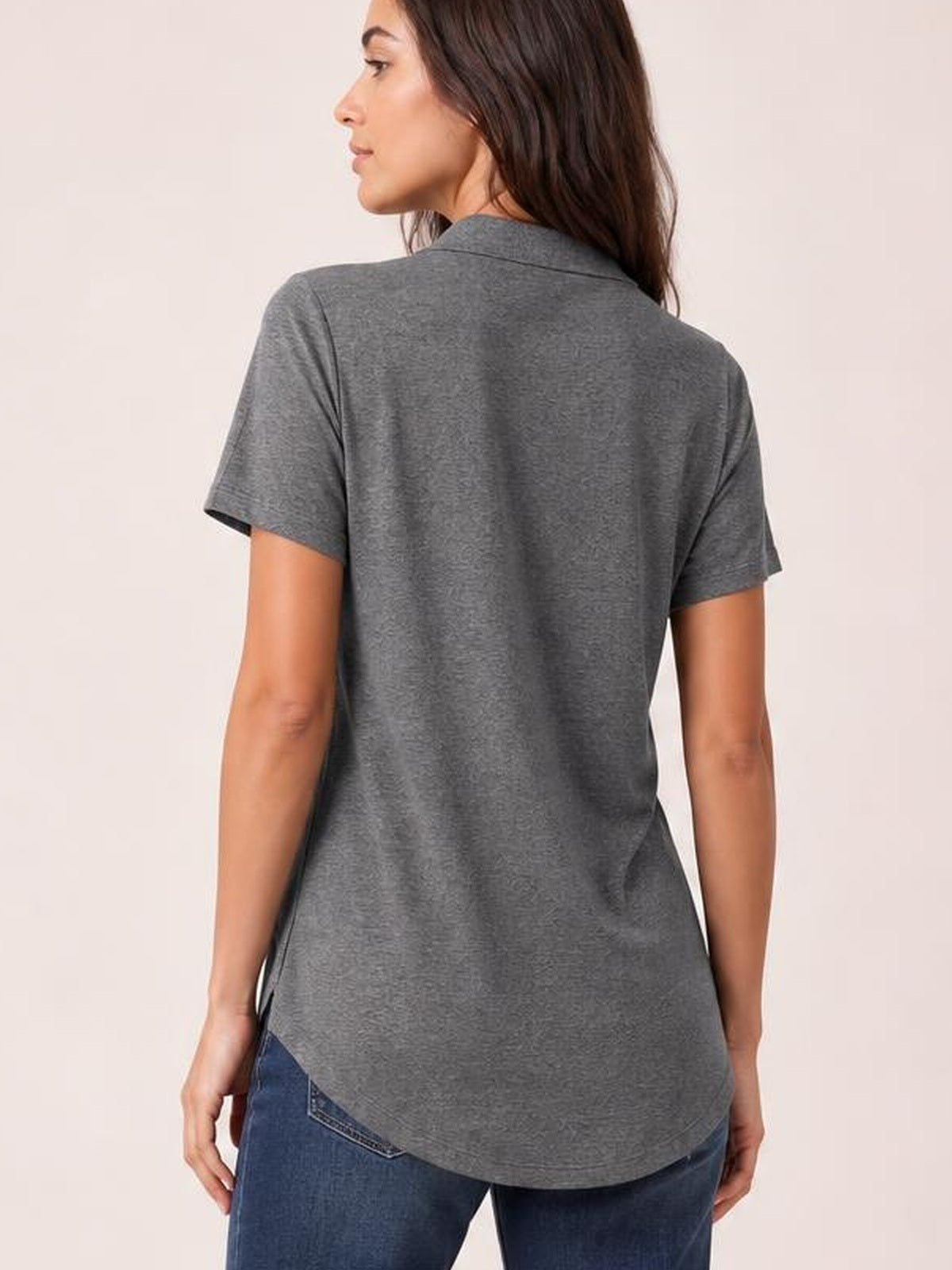 A model faces away wearing a gray short sleeve T-shirt with a collared neckline, relaxed silhouette, and curved longer back hem.