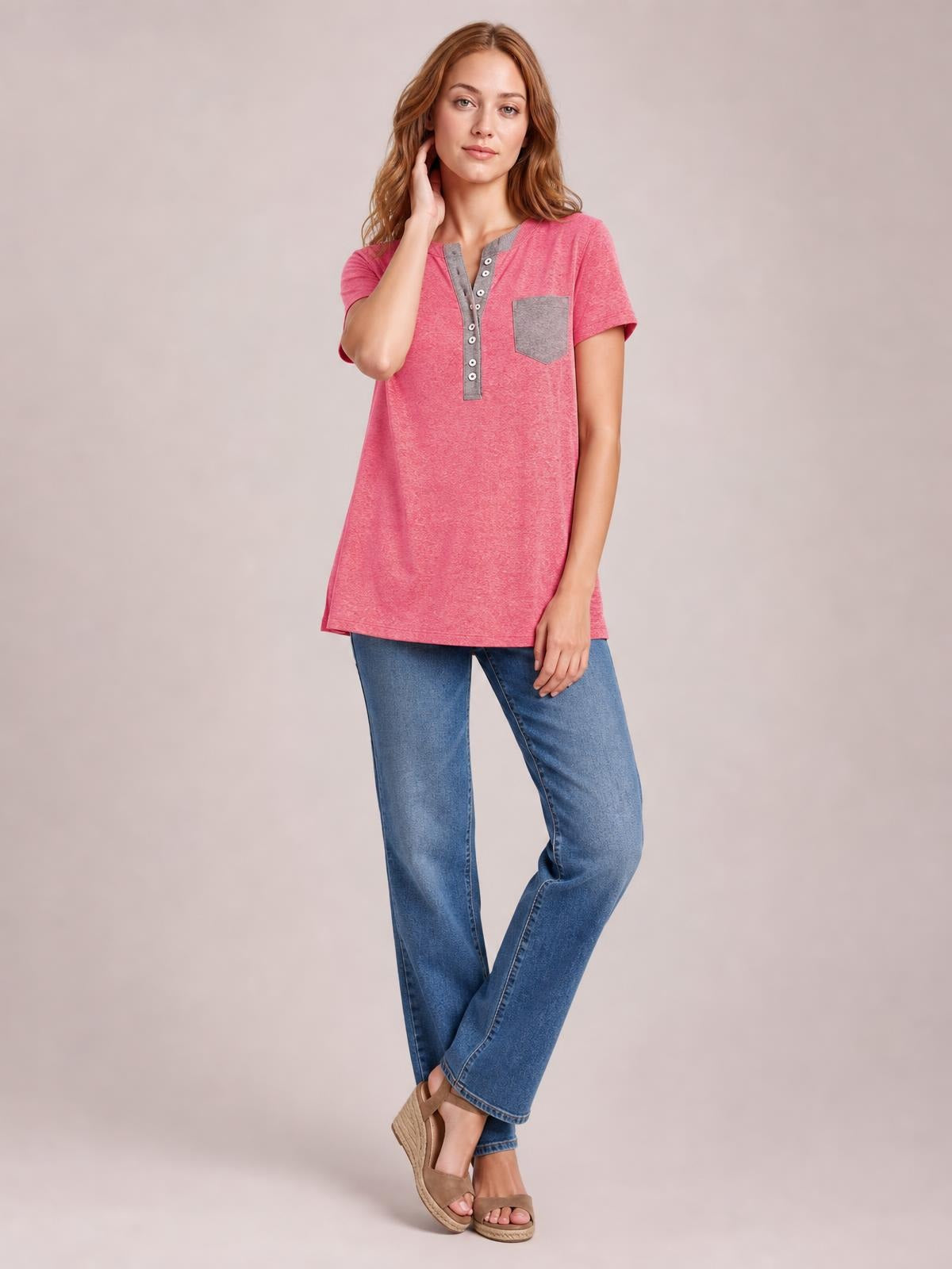 Model poses in a pink short-sleeve T-shirt with a gray half-button placket and chest pocket, featuring a relaxed longline silhouette.