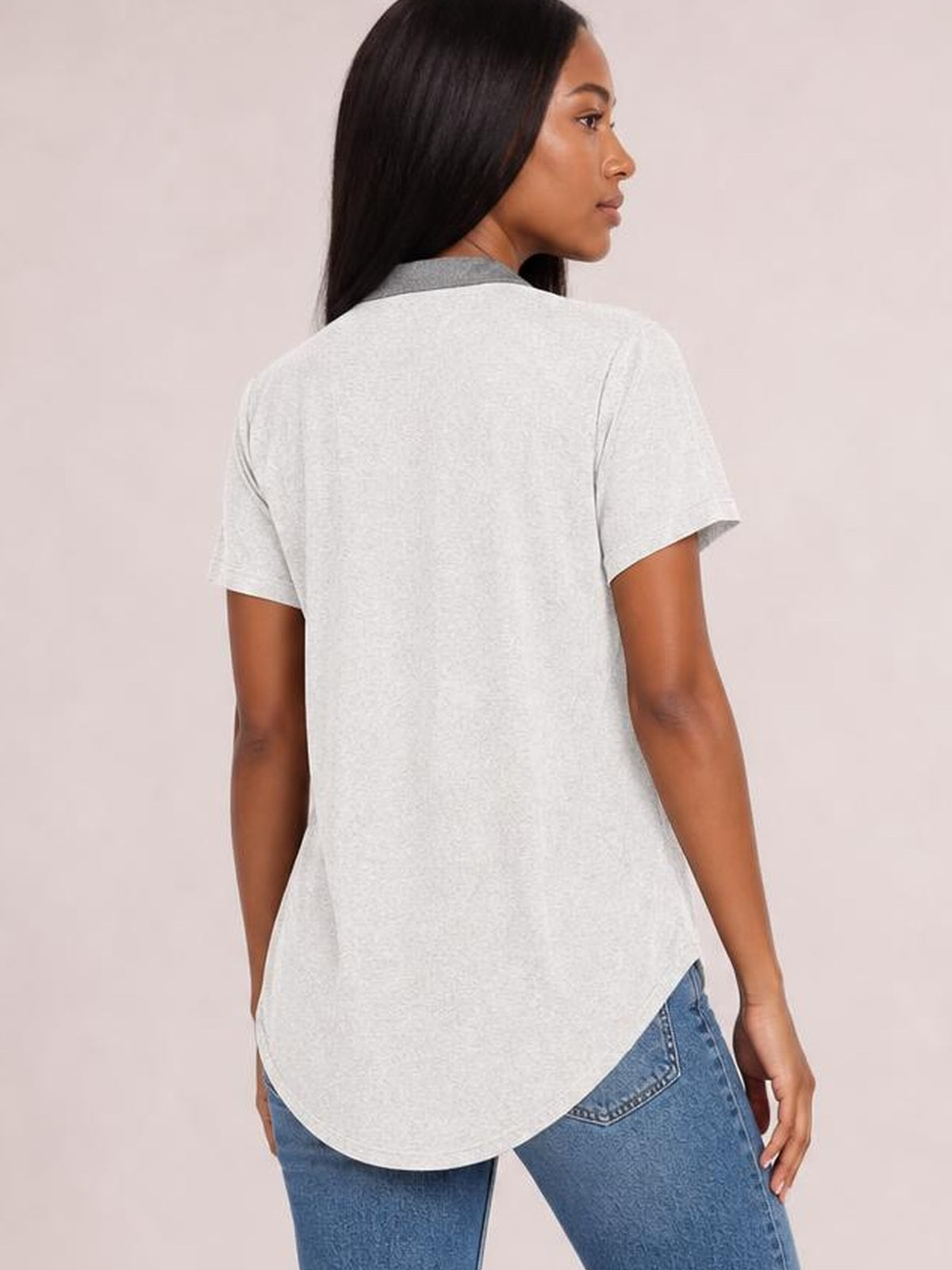 Model shown from the back wears a light gray half button short sleeve T-shirt with a relaxed silhouette, smooth construction, and rounded high-low hem.