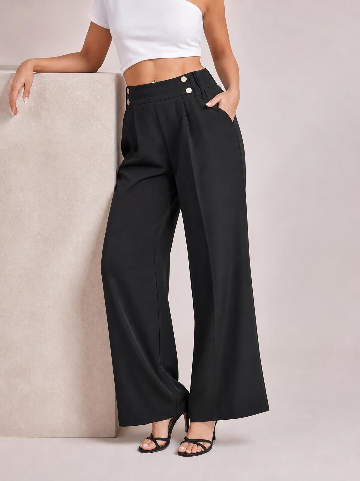 Model poses in black high-waisted wide-leg pants with front pleats, button details, side pockets, and a fluid full-length silhouette.