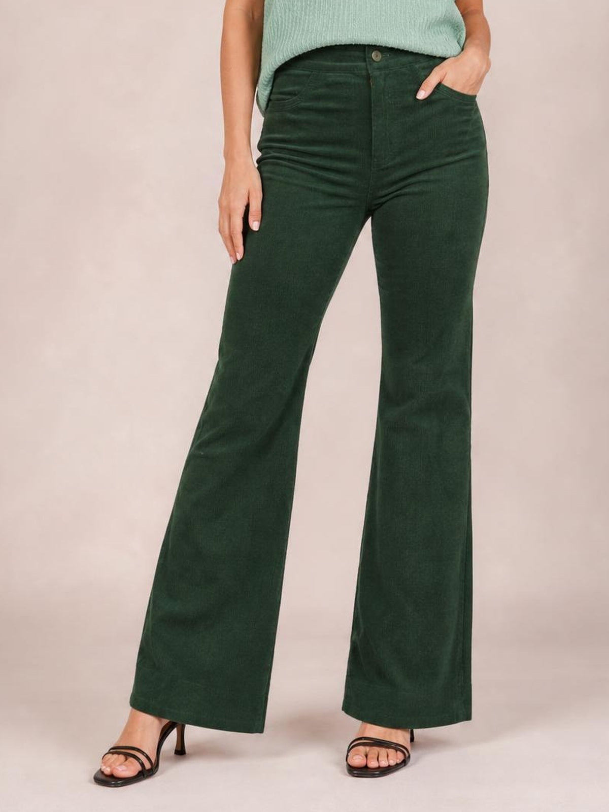 Model wearing dark green high-waist bootcut pants with a button closure, front pockets, fitted hips, and gently flared legs.