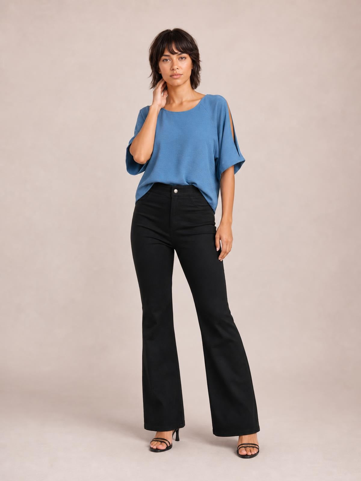 Model poses in black high-waist bootcut pants with a fitted upper leg, subtly flared hems, front button closure, and simple construction.