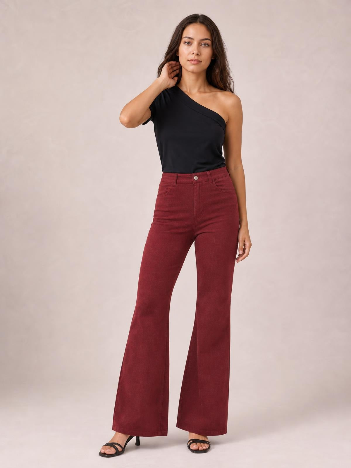 A model poses in high-waisted burgundy bootcut pants with a front button closure, belt loops, pockets, fitted hips, and gently flared legs.