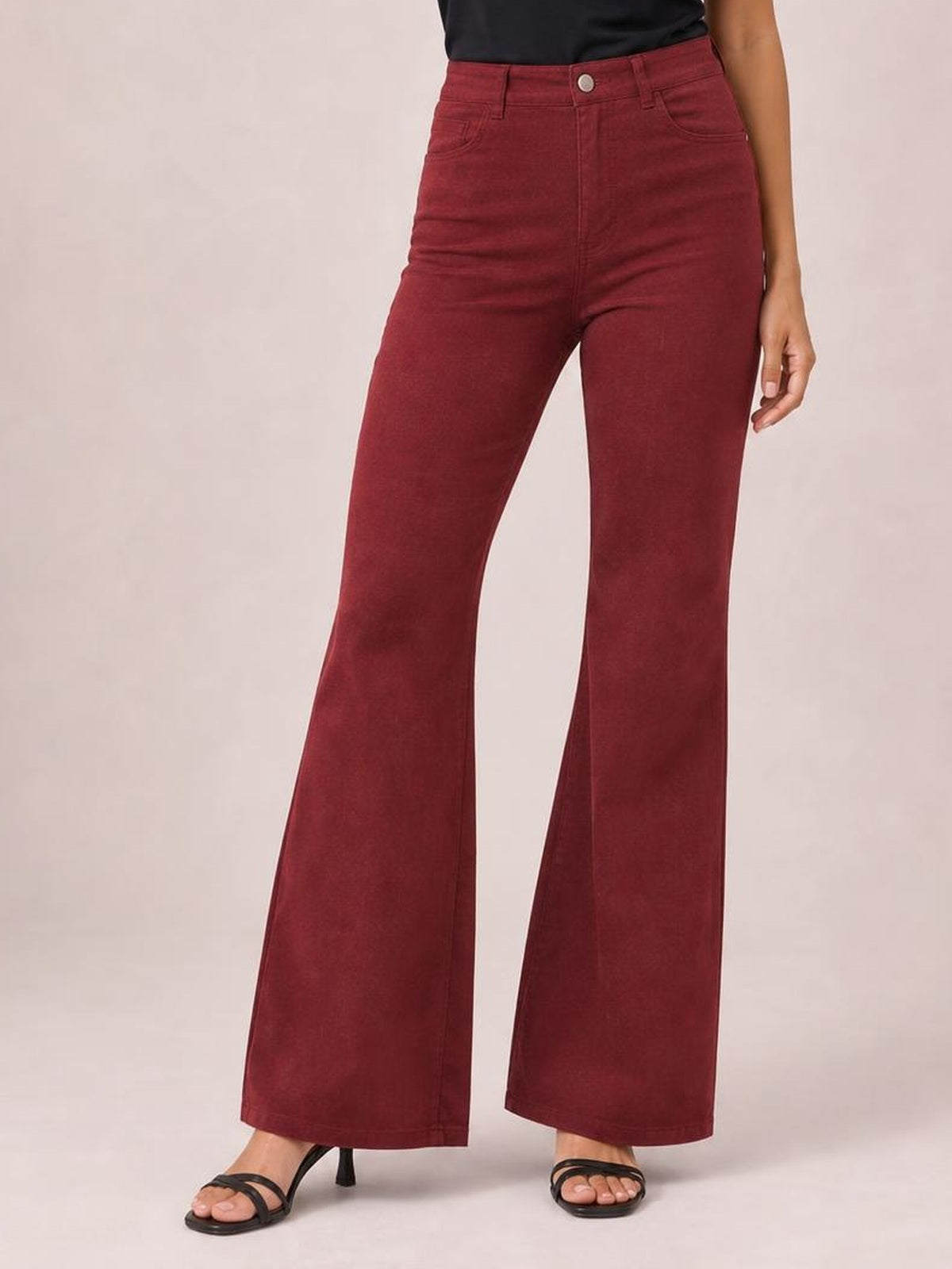 A standing model wears burgundy high-waisted bootcut pants with a fitted hip, button waistband, belt loops, front pockets, and gently flared legs.