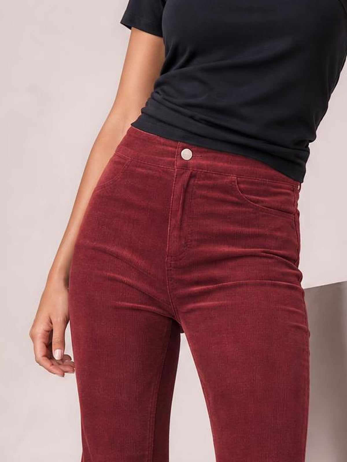 Model wearing high-waisted burgundy bootcut pants with a fitted silhouette, front button closure, belt loops, curved pockets, and visible seam detailing.