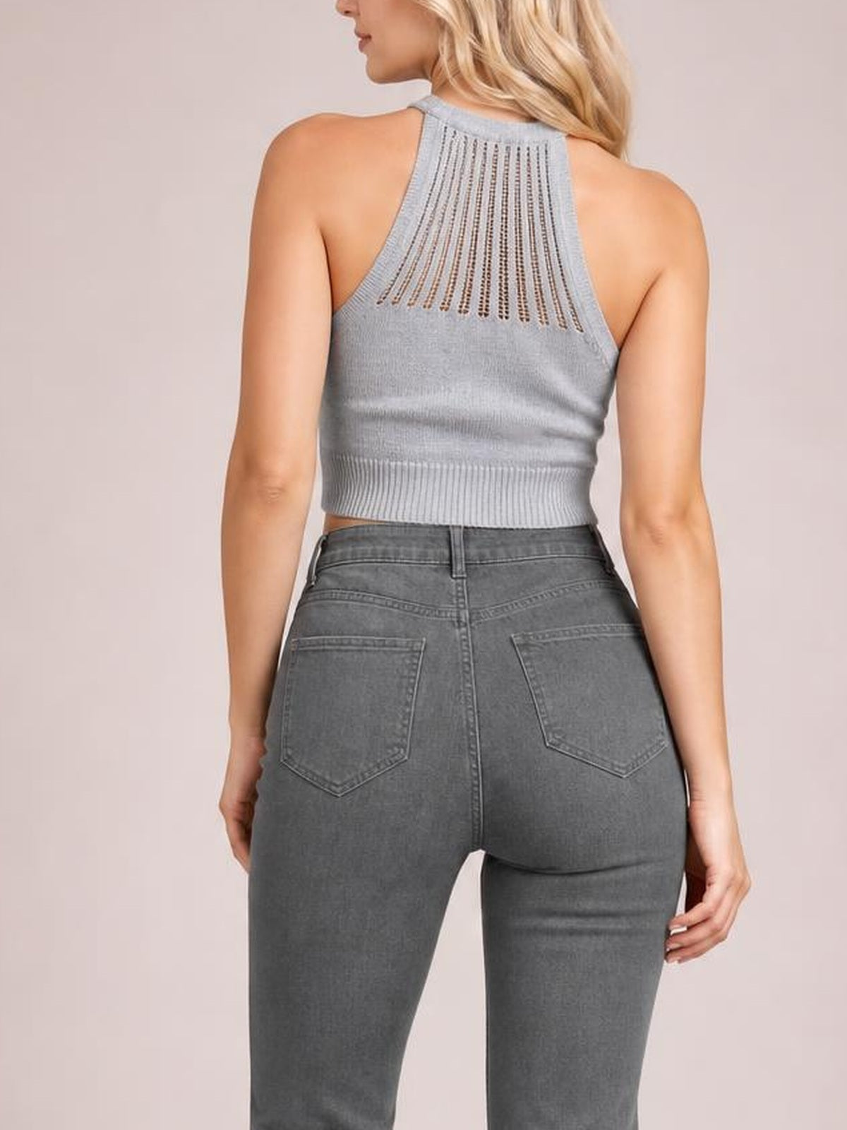 A model stands with her back to the camera in gray high-waist bootcut pants featuring belt loops, rear patch pockets, and a fitted silhouette.
