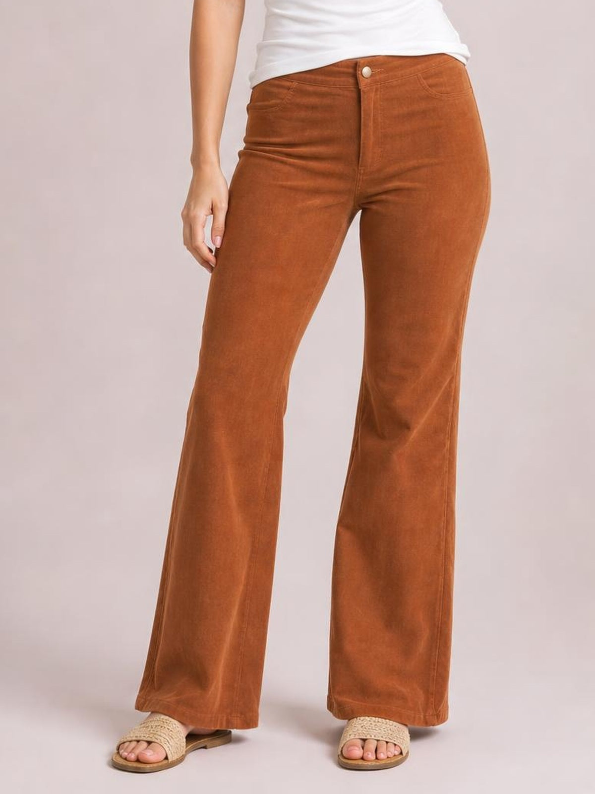 Model wears high-waisted rust-brown bootcut pants with a fitted silhouette, front button closure, subtle pockets, and gently flared hems.