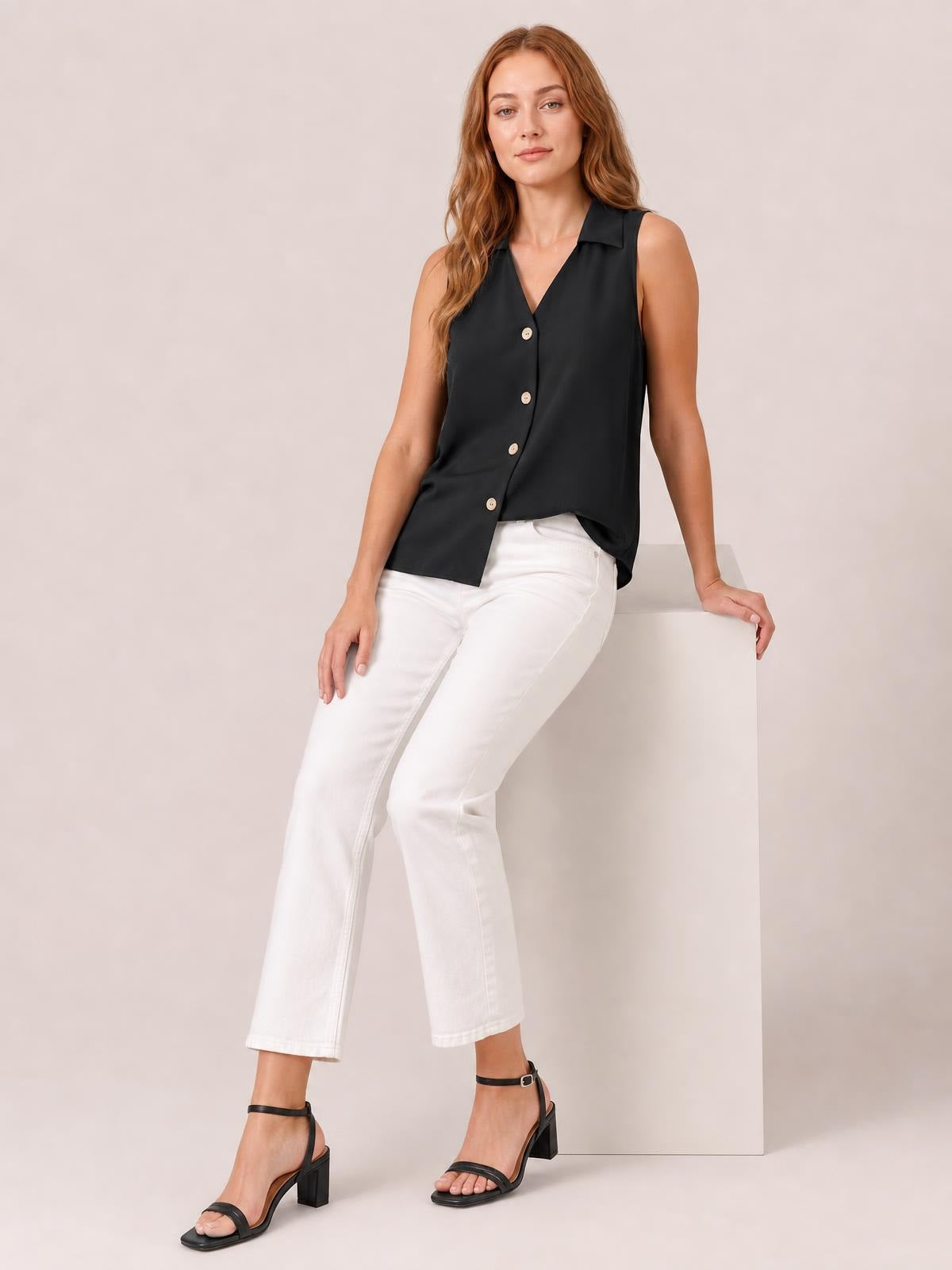 Model poses in a black Johnny collar button-up tank with sleeveless styling, a relaxed silhouette, V-neckline, and visible front buttons.