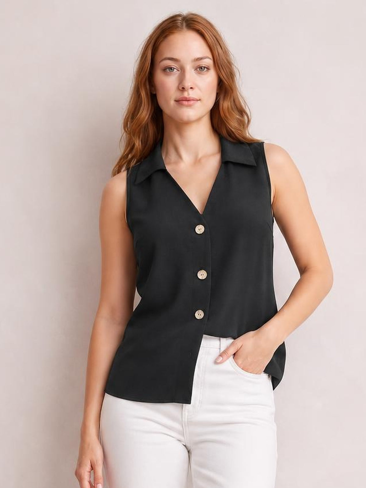 Model poses with one hand in her pocket wearing a black Johnny collar button-up tank with a V-neck, sleeveless cut, front buttons, and relaxed silhouette.