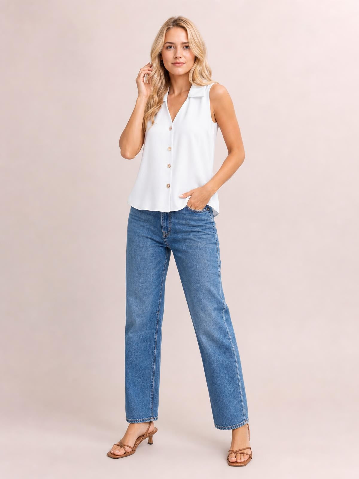 Model wearing a white Johnny collar button-up tank with a sleeveless cut, front buttons, relaxed silhouette, and curved hem, posing with one hand in her pocket.