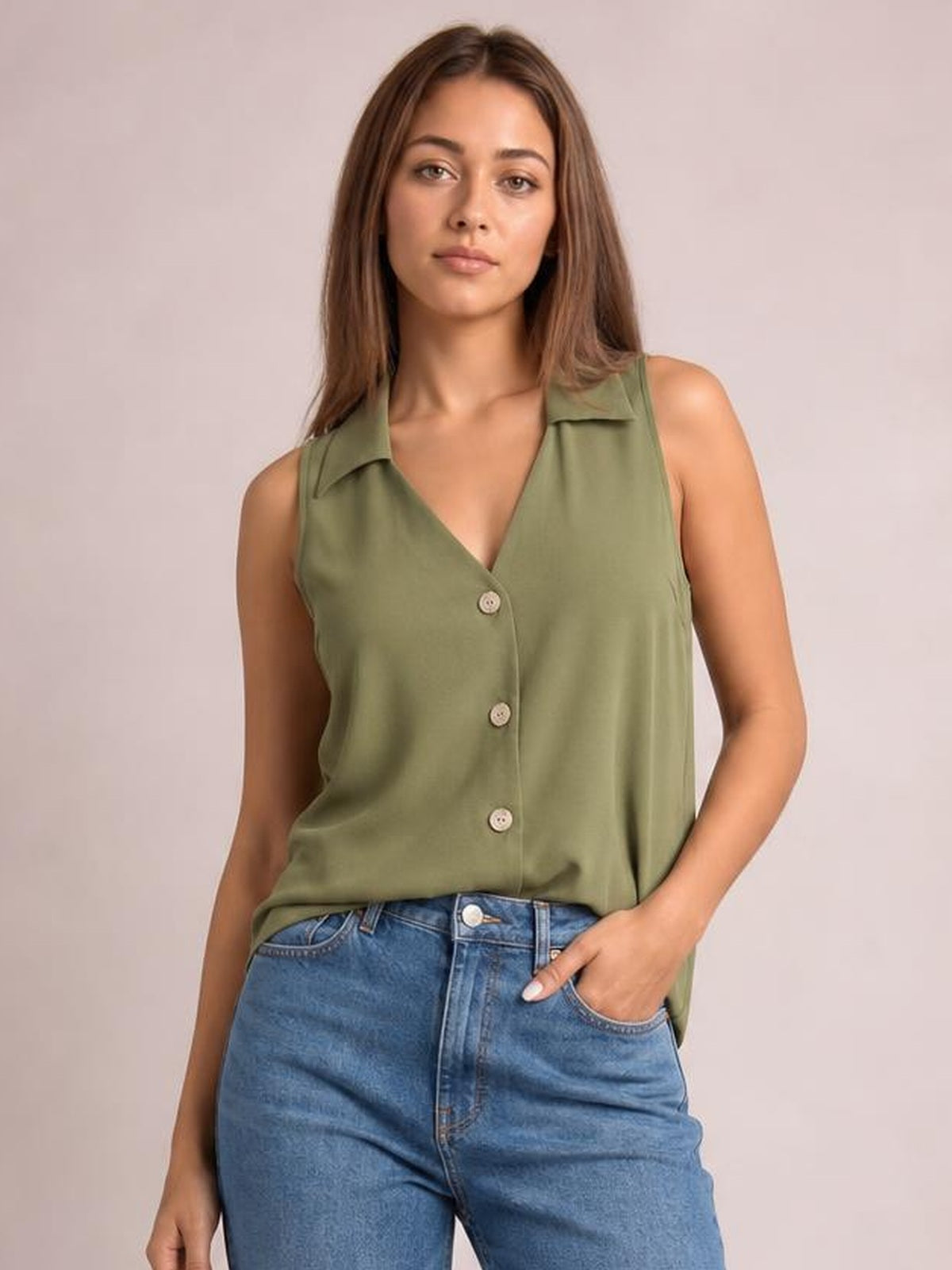 Model poses with one hand in her jeans pocket, wearing an olive green Johnny collar button-up tank with a sleeveless, relaxed silhouette and front buttons.