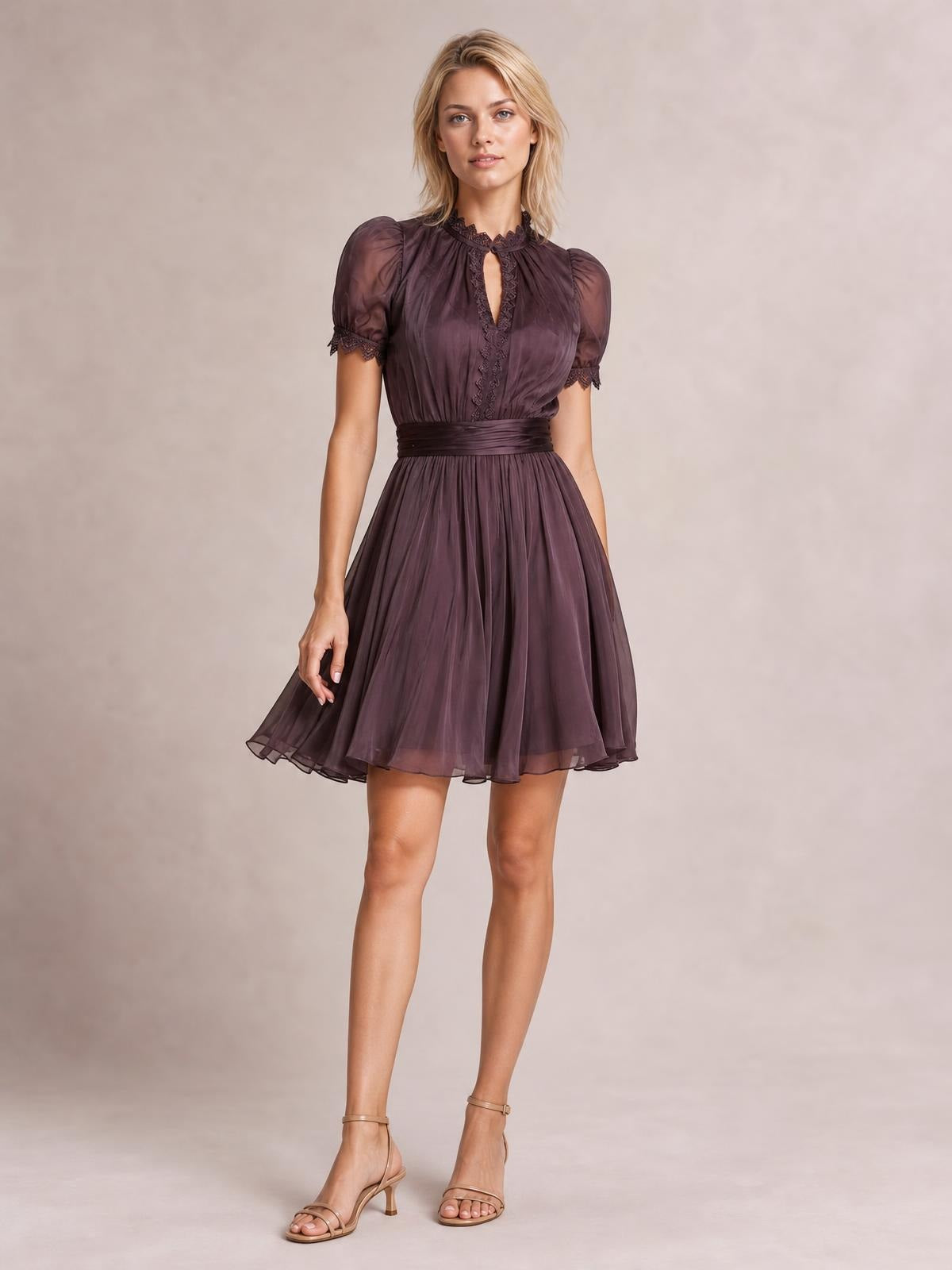 A model stands in a dark plum A-line dress with puff sleeves, lace-trimmed neckline and cuffs, a defined waist, and a softly flared knee-length skirt.