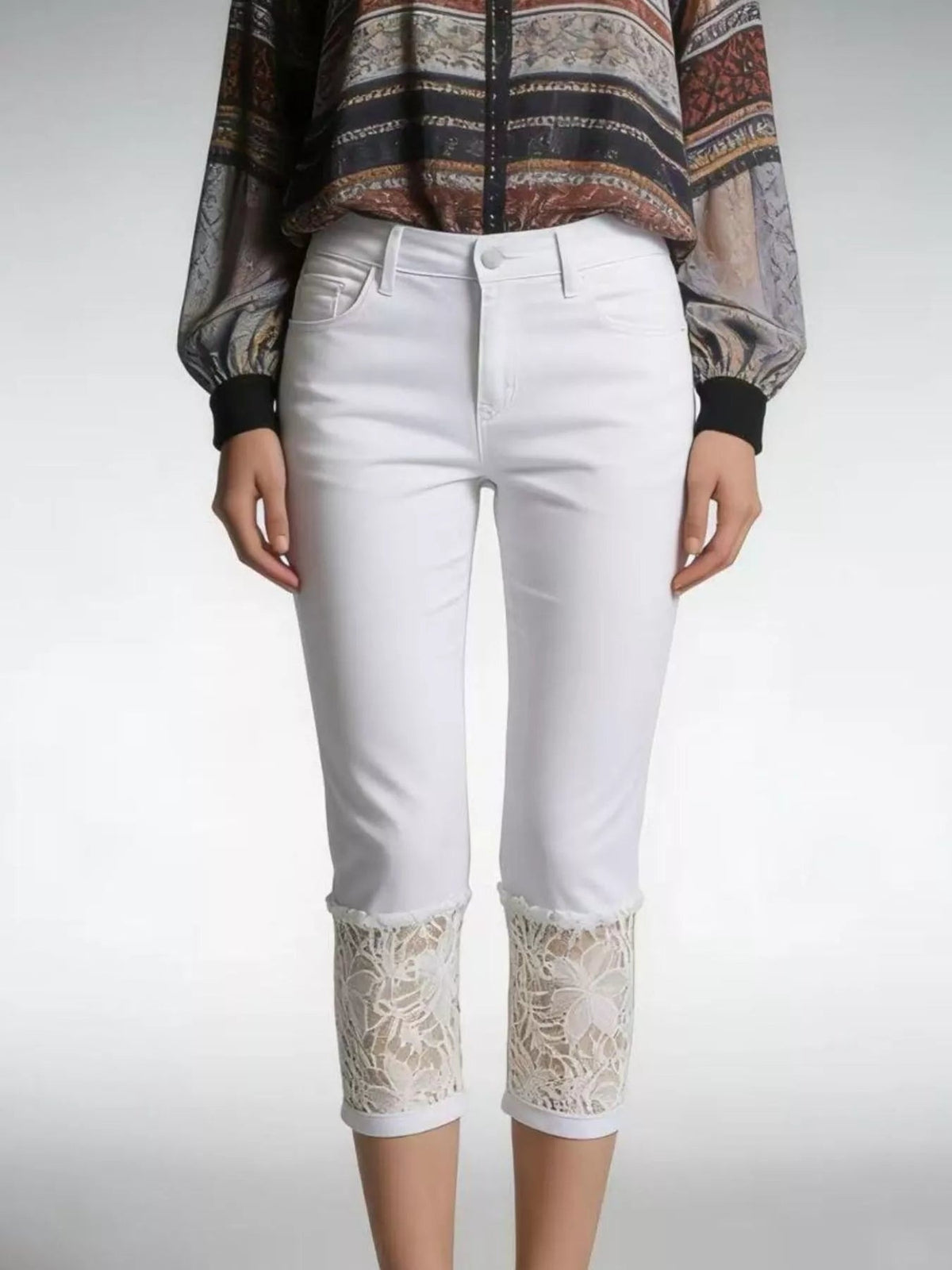 Model stands with hands at her sides wearing white Lace Trimmed Capri Jeans with a button closure, front pockets, slim fit, and floral lace panels at the hems.