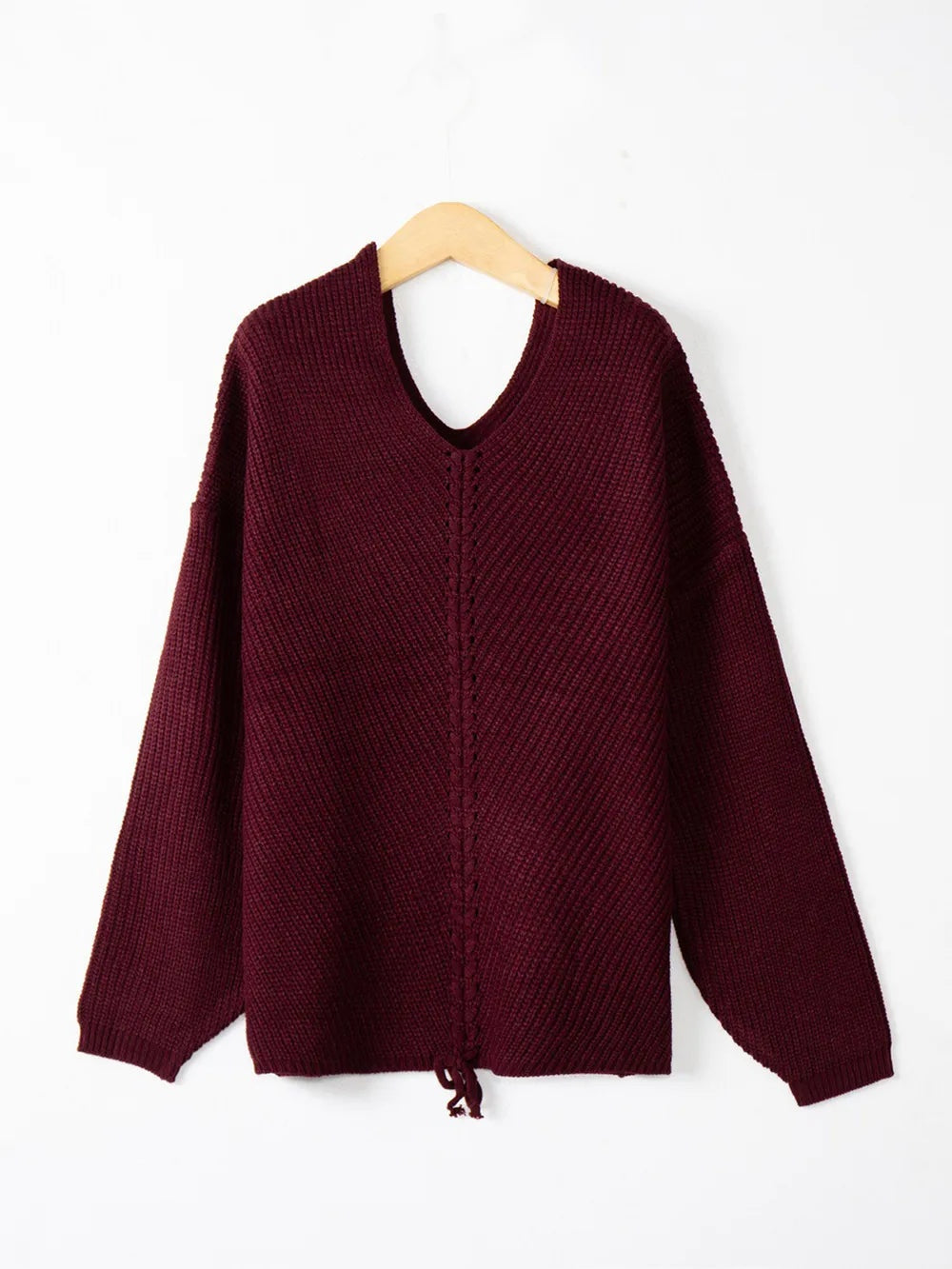 Burgundy knit sweater with a V-neck, long sleeves, relaxed silhouette, and visible lace-up detail running down the center front.
