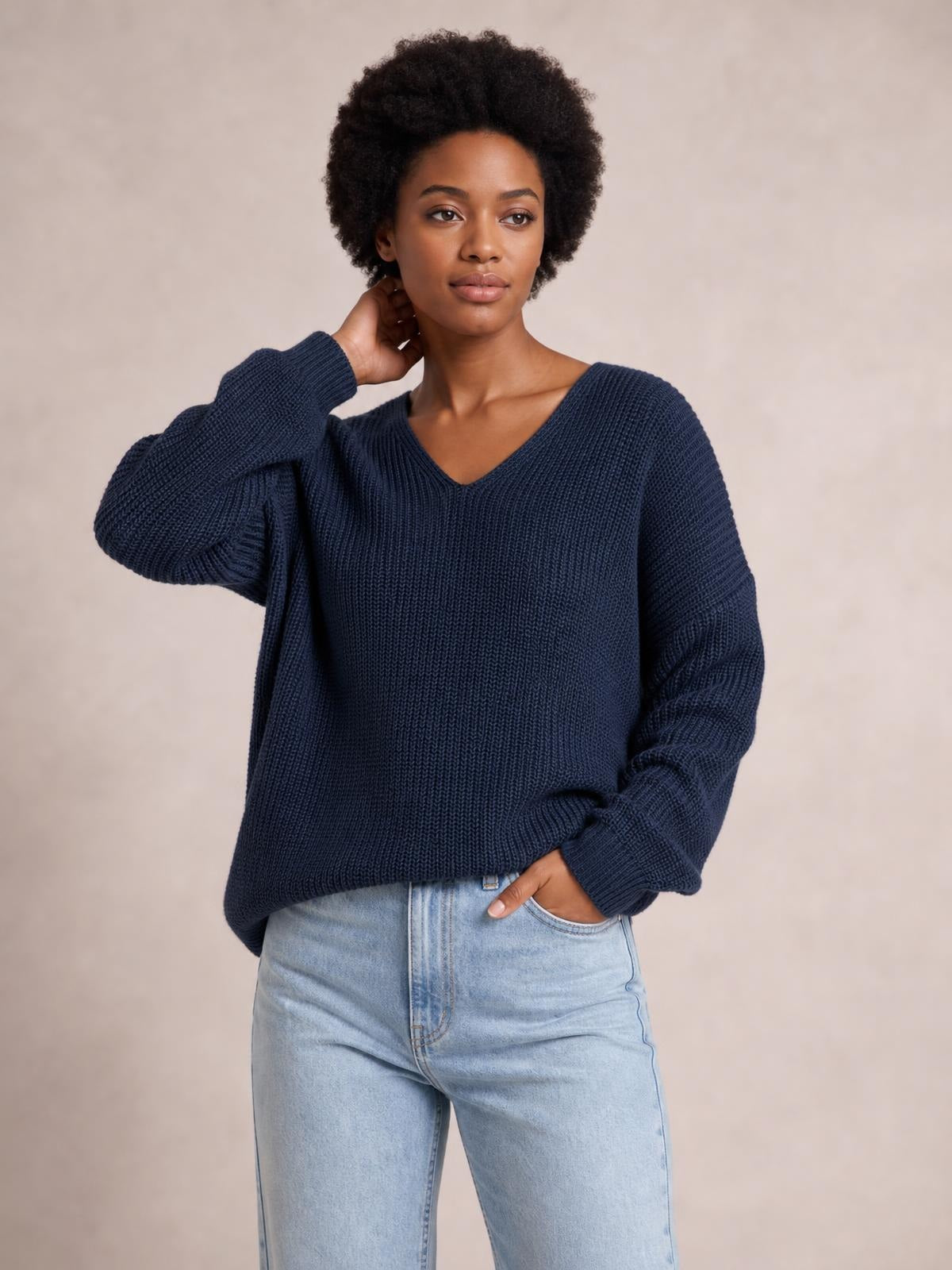 Model wears a navy ribbed-knit long-sleeve V-neck sweater with a relaxed oversized silhouette, dropped shoulders, and wide ribbed cuffs.