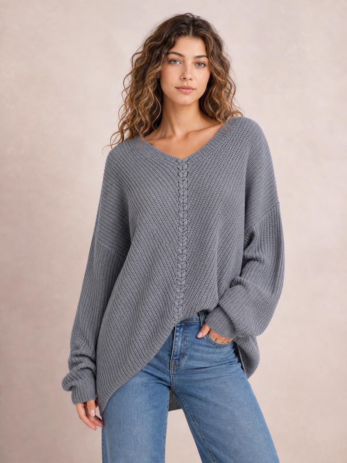 Model wears a gray lace-up V-neck long sleeve sweater with textured knit construction, relaxed oversized silhouette, dropped shoulders, and elongated cuffs.