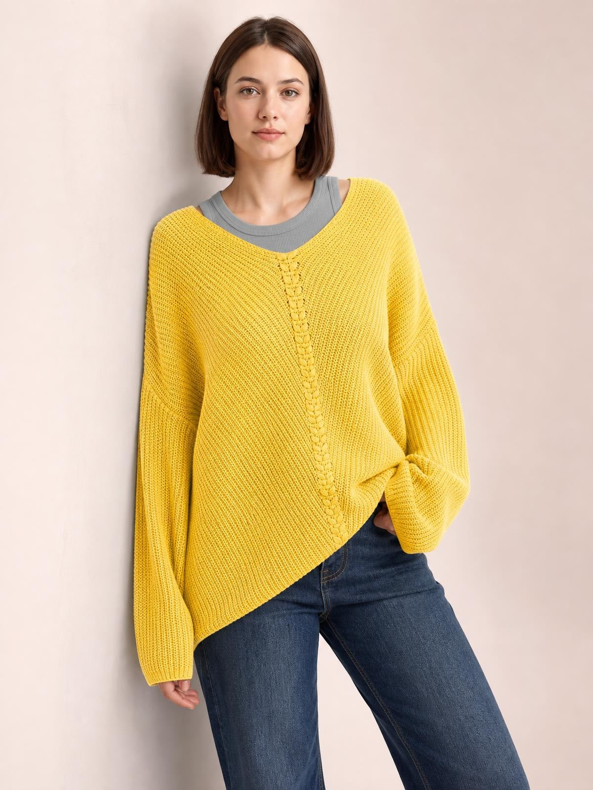 A model wears a mustard-yellow lace-up V-neck long-sleeve sweater with a textured knit, relaxed oversized silhouette, and dropped shoulders.