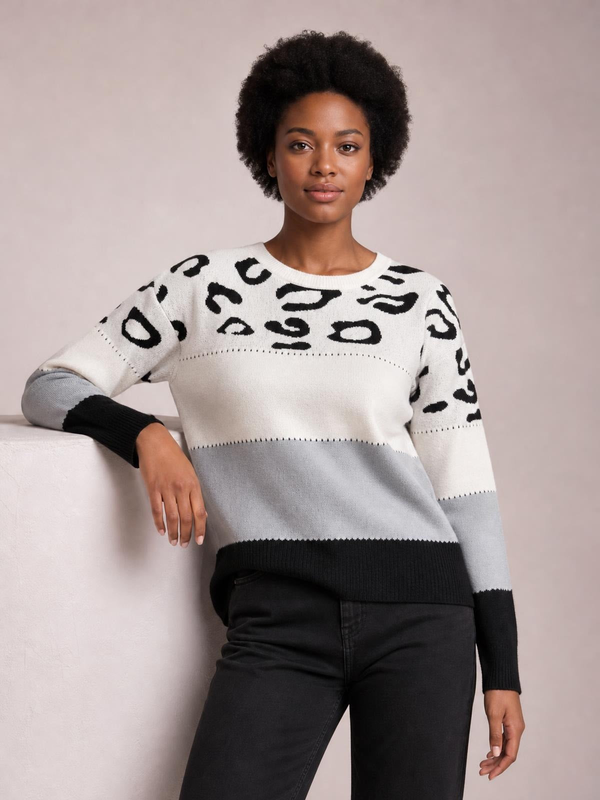 A model poses in a relaxed-fit leopard color block long sleeve sweater with an ivory crew neck, black print, gray lower panel, and ribbed black cuffs and hem.