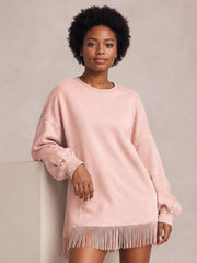 A plus-size blush pink mini dress features a relaxed silhouette, long sleeves, ribbed neckline and cuffs, visible seam details, and a fringed hem.