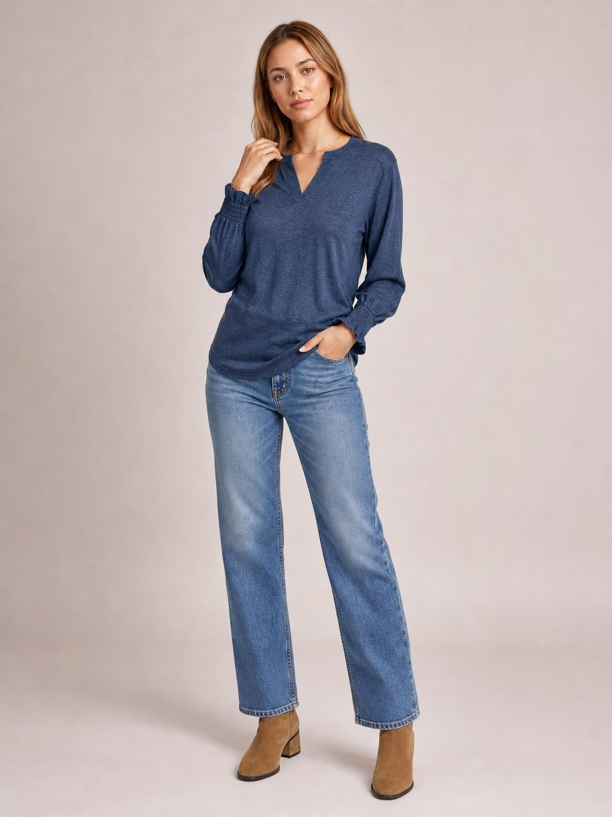 Model poses in a blue notched long sleeve T-shirt with a relaxed silhouette, subtle ruffled cuffs, and a slightly curved hem.