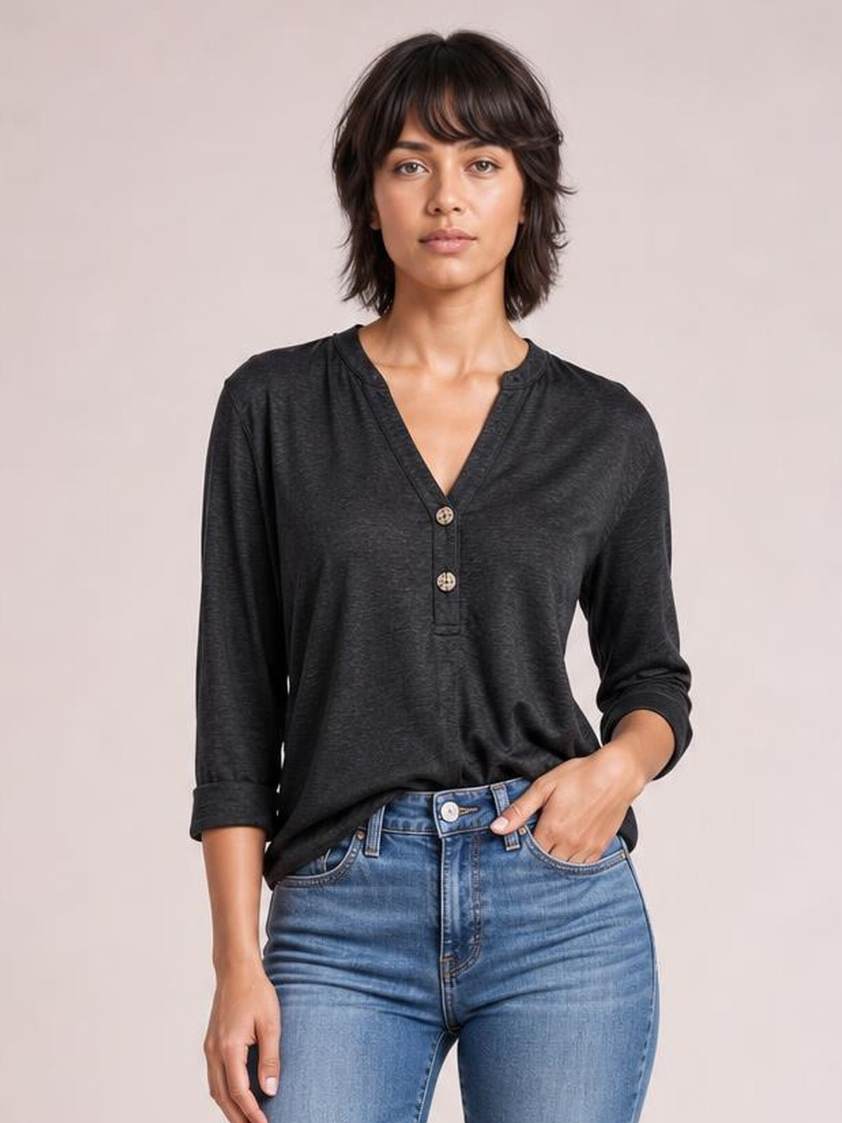 Model wearing a black notched long sleeve T-shirt with a relaxed silhouette, V-neckline, two-button placket, and rolled cuffs.