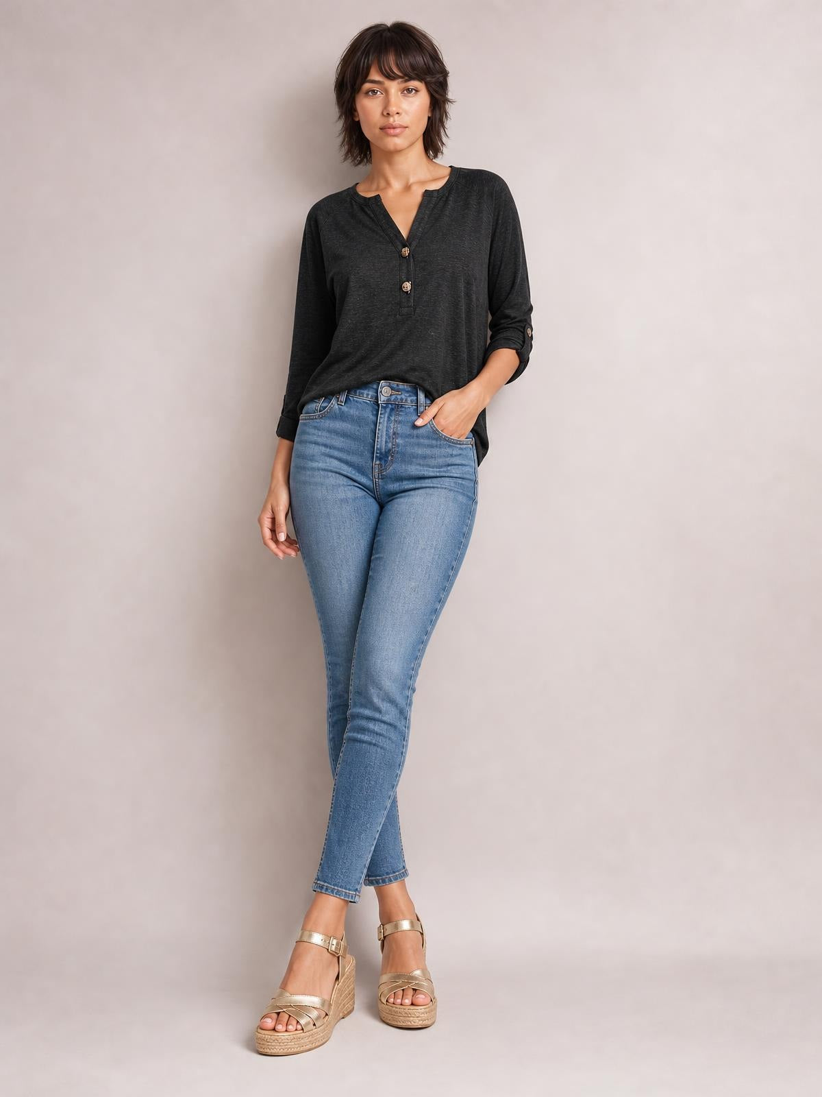 Model poses in a black notched long sleeve T-shirt with a buttoned neckline, relaxed silhouette, and slightly rolled sleeves.