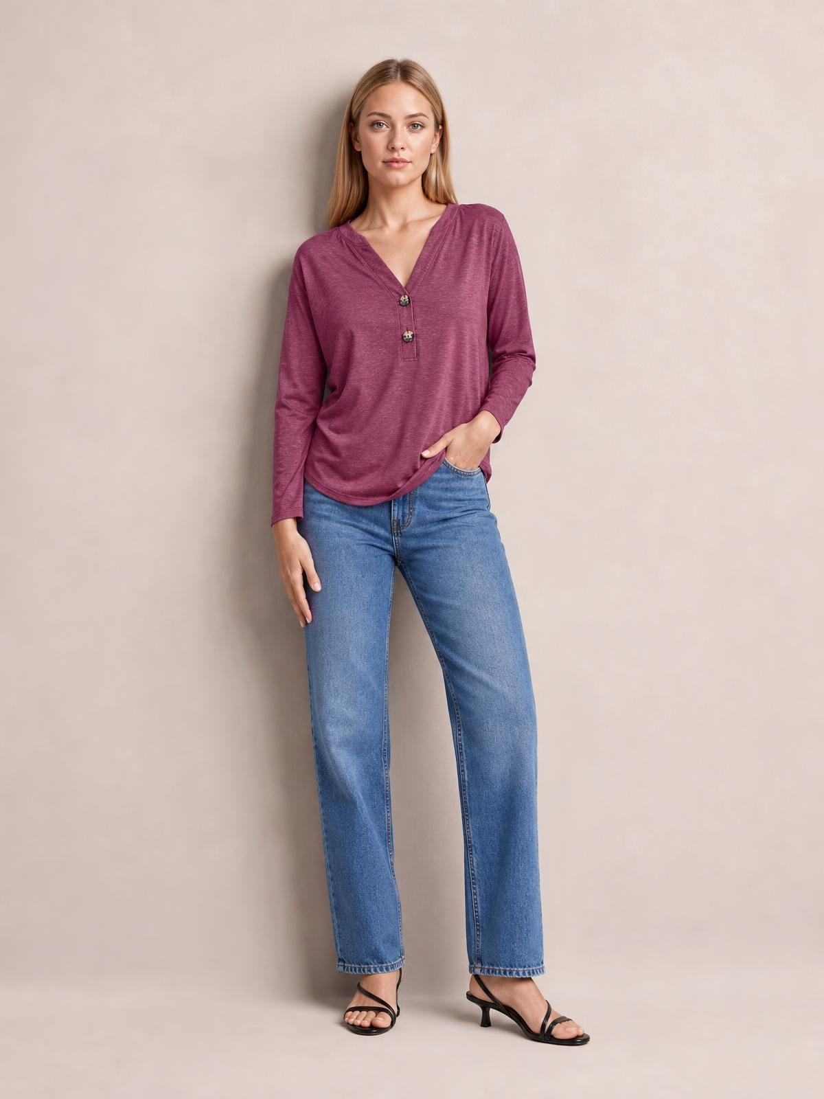 Model wears a burgundy notched long sleeve T-shirt with a relaxed silhouette, V-neckline, buttoned placket, and slight stretch.