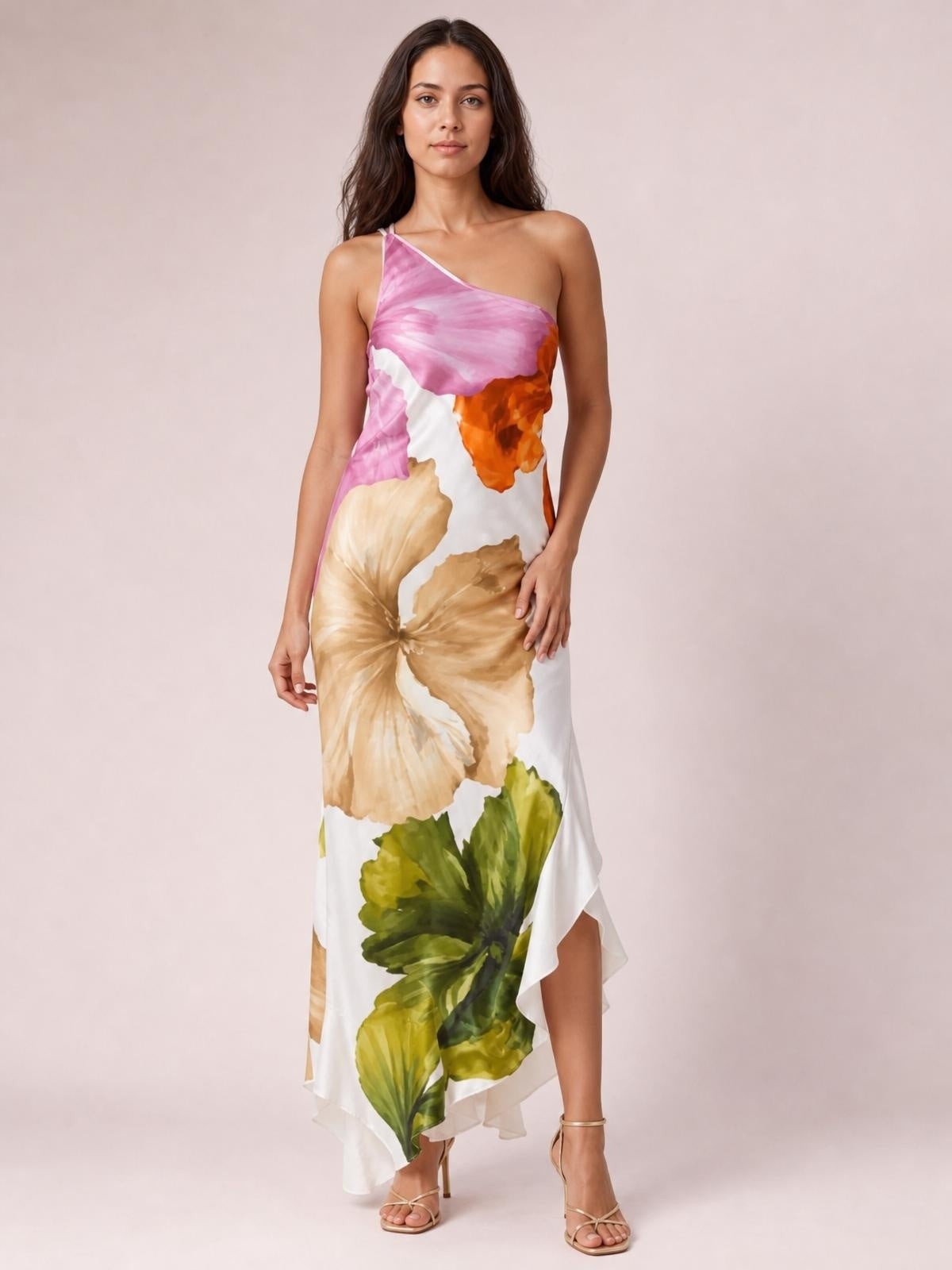 Model stands in a floral print satin maxi dress with a pink, orange, cream, and green palette, one-shoulder neckline, fitted silhouette, and asymmetric hem.