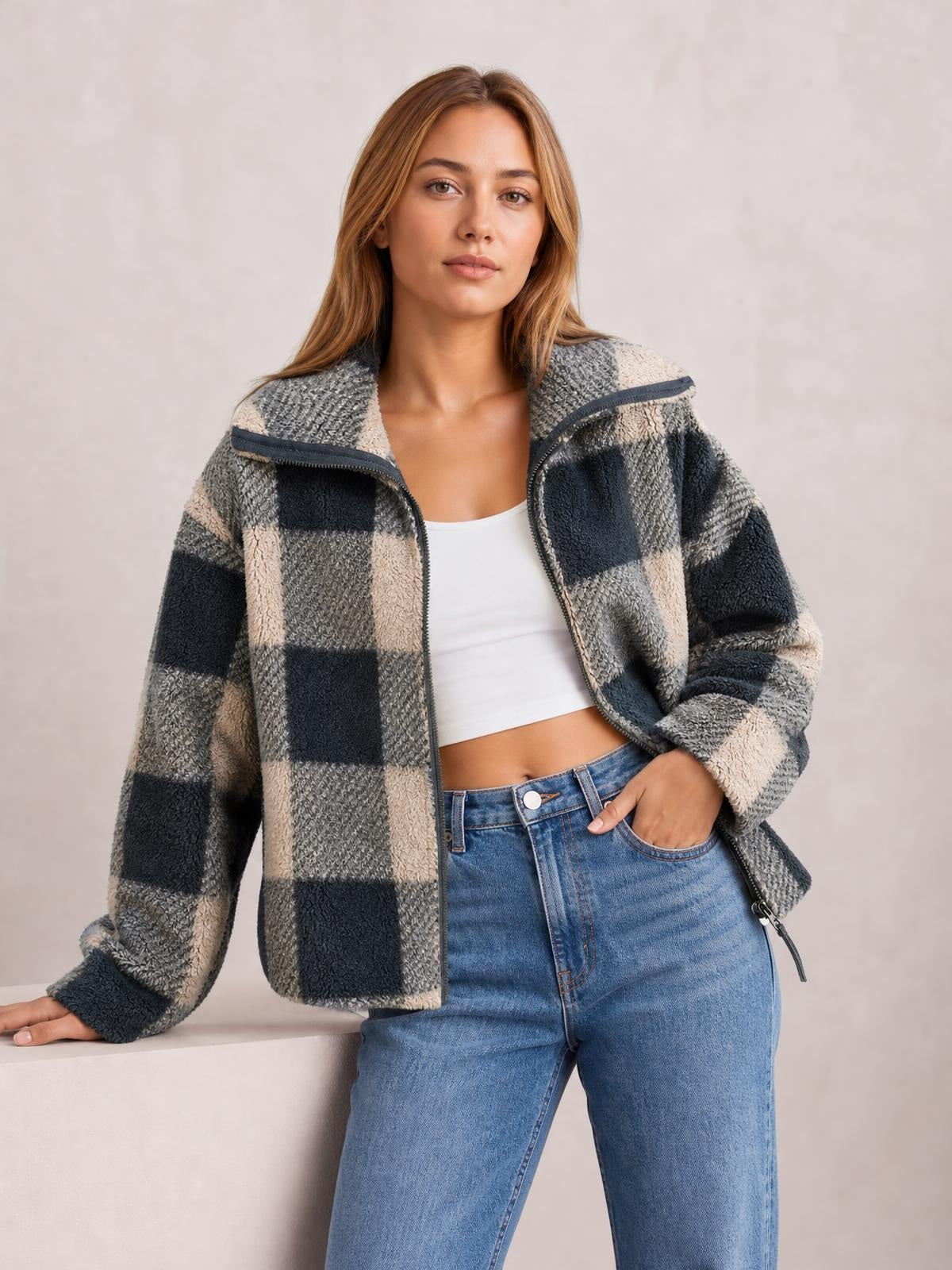 Model wearing a gray, cream, and navy plaid zip-up jacket with long sleeves, a relaxed boxy silhouette, textured fleece finish, and an open front.
