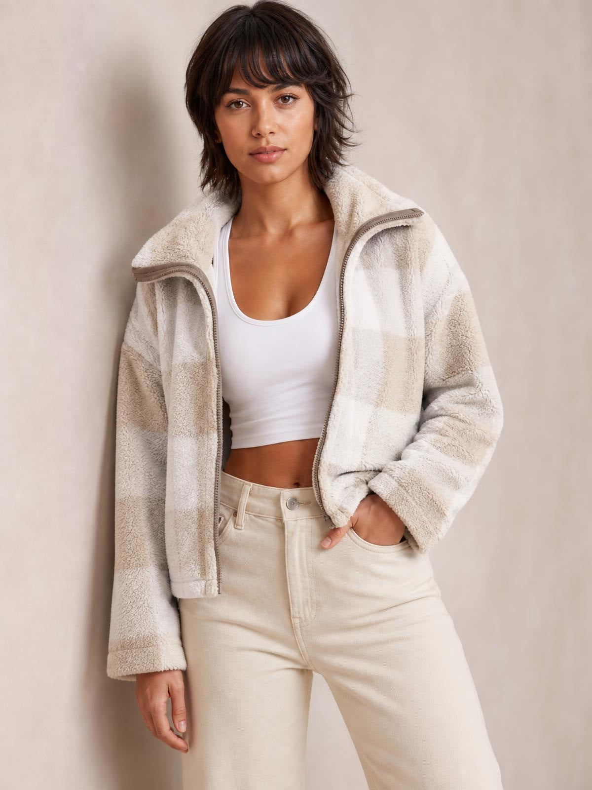 A model poses in an open cream zip-up jacket with a textured fleece finish, high collar, long sleeves, and a relaxed silhouette.