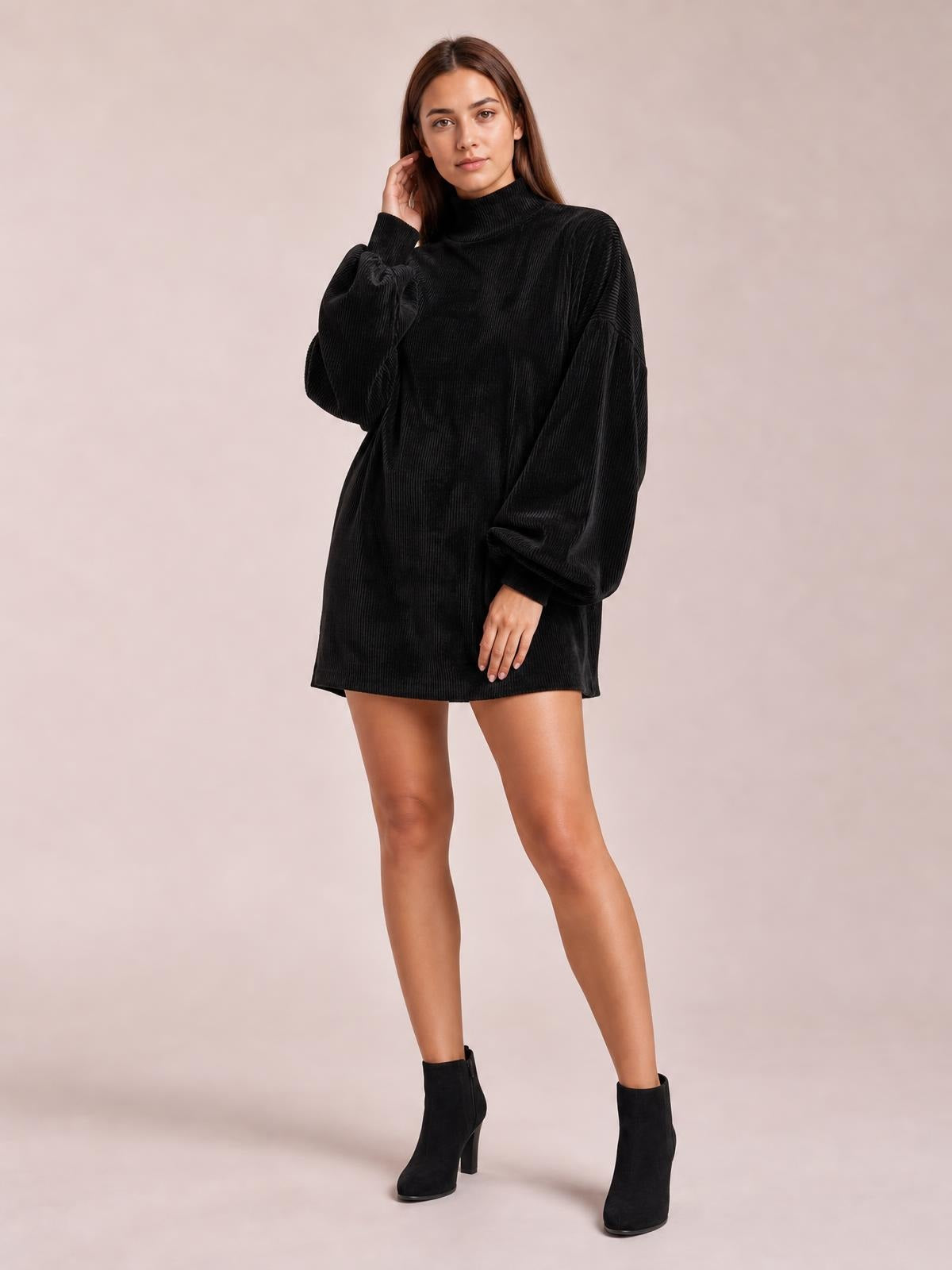 A model poses in a black ribbed mock neck mini dress with a relaxed silhouette, long lantern sleeves, and fitted cuffs.