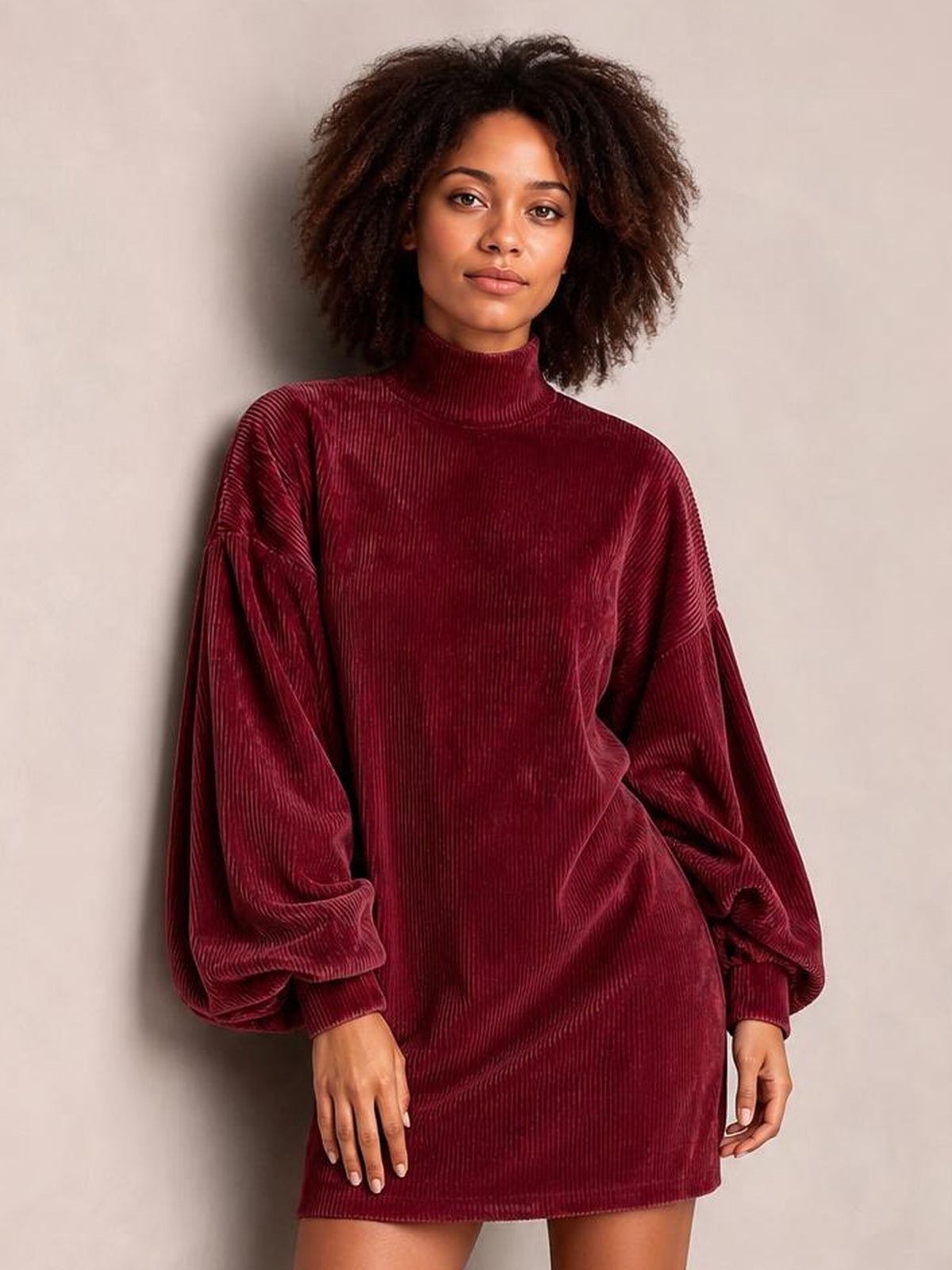 Model wearing a burgundy ribbed mock neck mini dress with a straight silhouette, oversized lantern sleeves, and gathered cuffs.