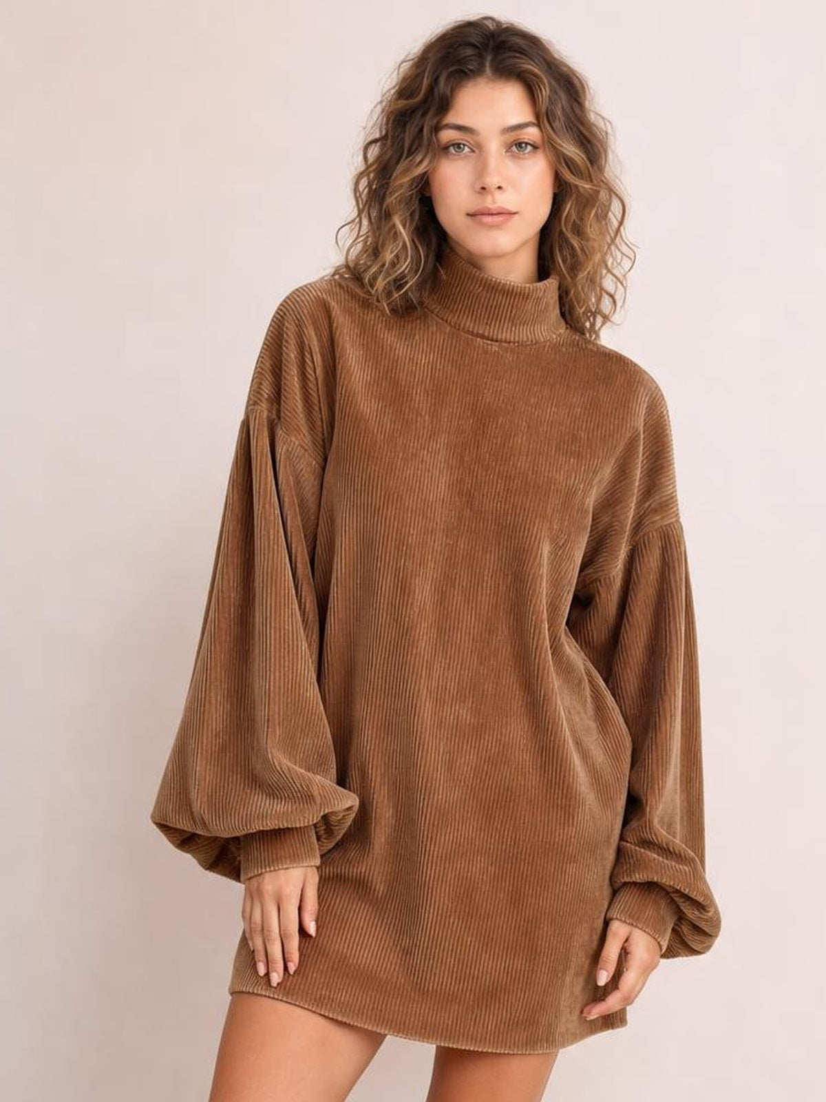 A model stands in a brown ribbed mock neck mini dress with voluminous lantern sleeves, a relaxed straight silhouette, and hands resting near the hem.