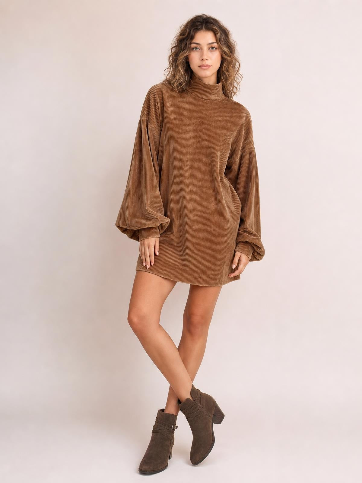 A model poses with crossed legs in a brown ribbed mock neck mini dress featuring voluminous lantern sleeves, fitted cuffs, and a relaxed straight silhouette.